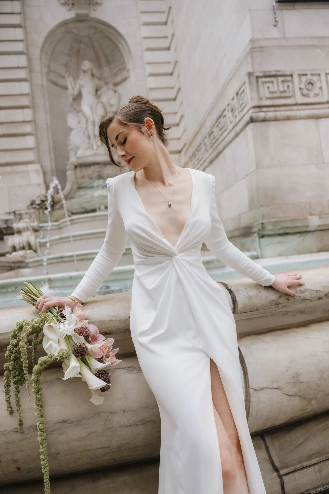 Bride in New York with a bridal bouquet of pink cymbidium orchids, white calla lilies, and allium flowers, with a trailing green amaranth flower