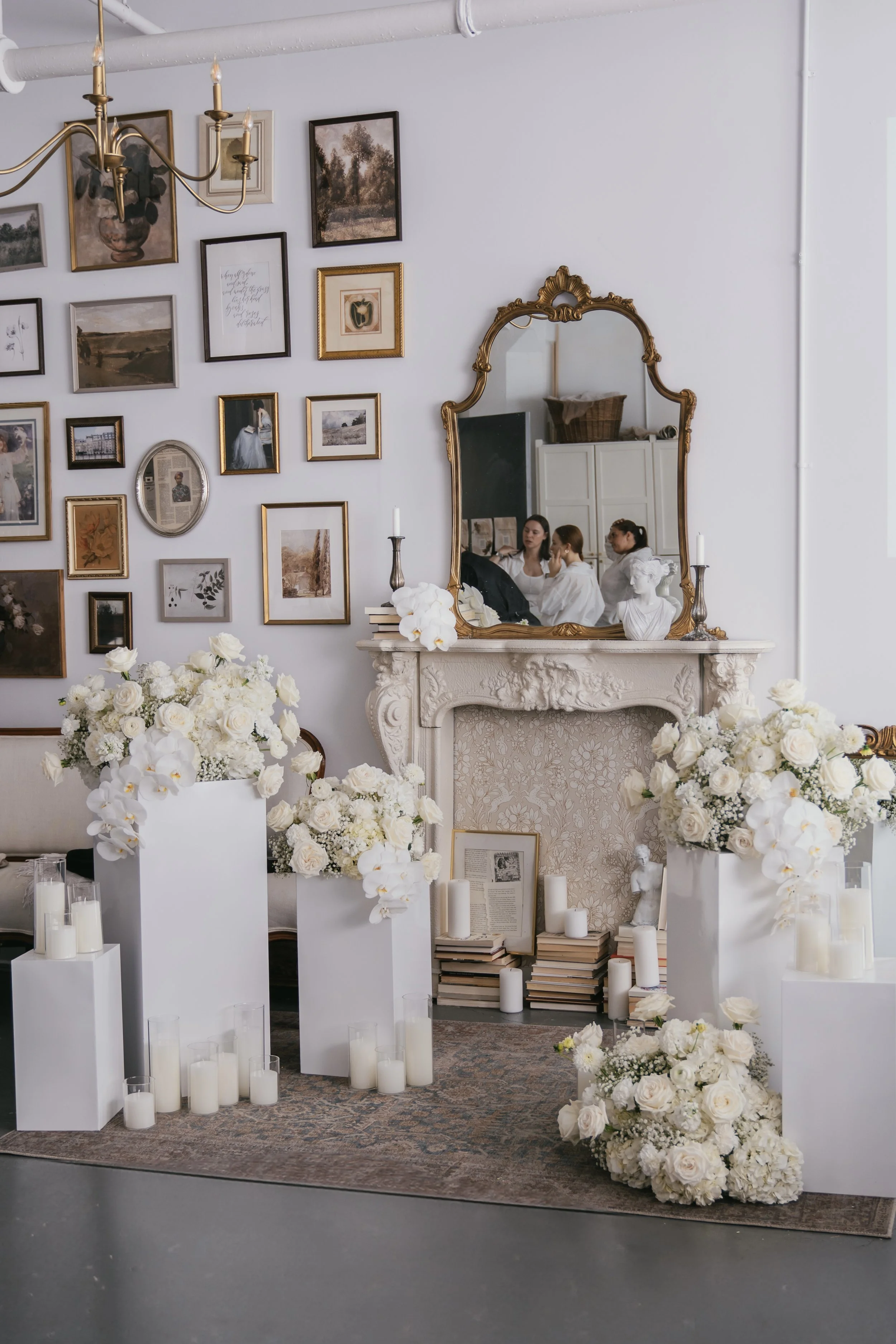 Ceremony setup for an intimate wedding in front of the fireplace decorated with white pedestals, candles and dreamy floral arrangements made with gypsophila (baby's breath), roses, carnation and stock flowers