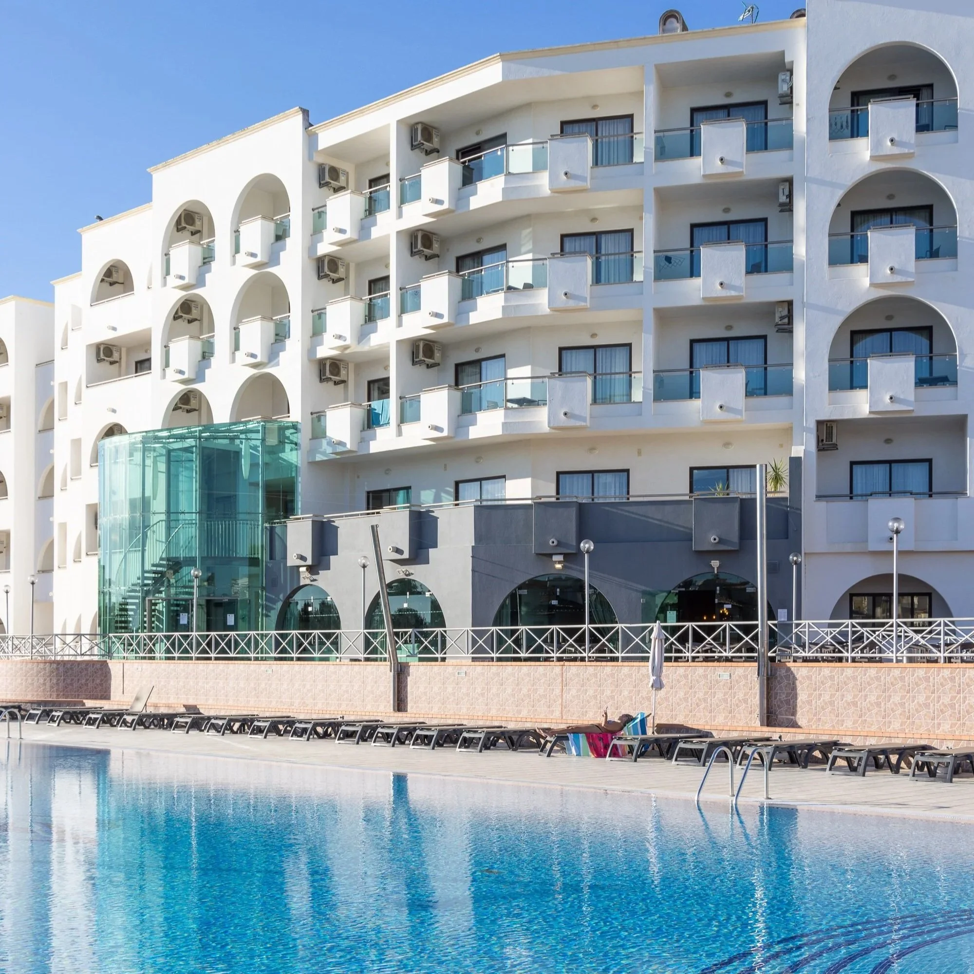 Man playing padel on a blue court holding a red and white racket during padel holiday.