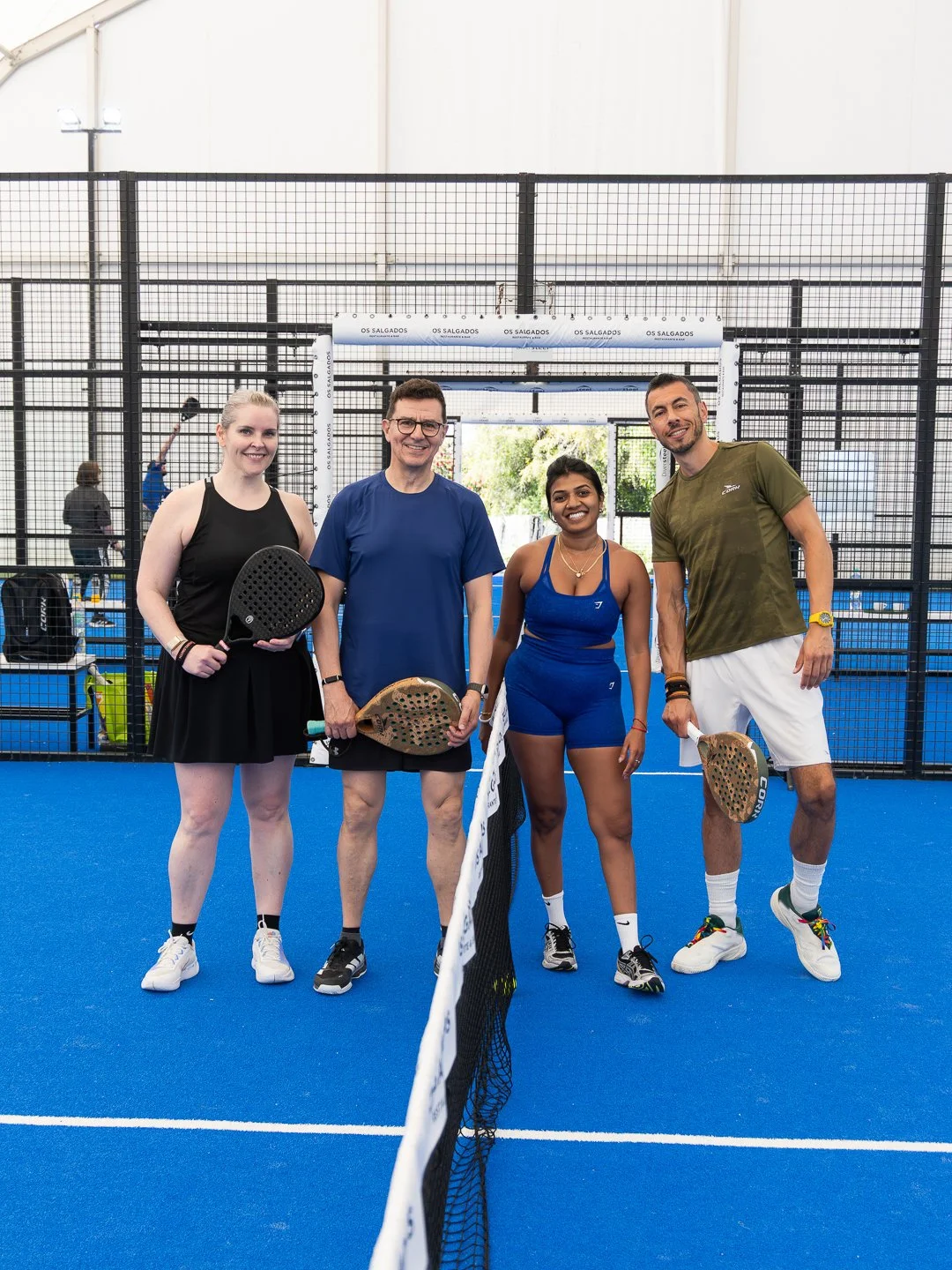 Padel coach showing a participant how to hold the racket properly, with a basket of tennis balls nearby during padel training camp.