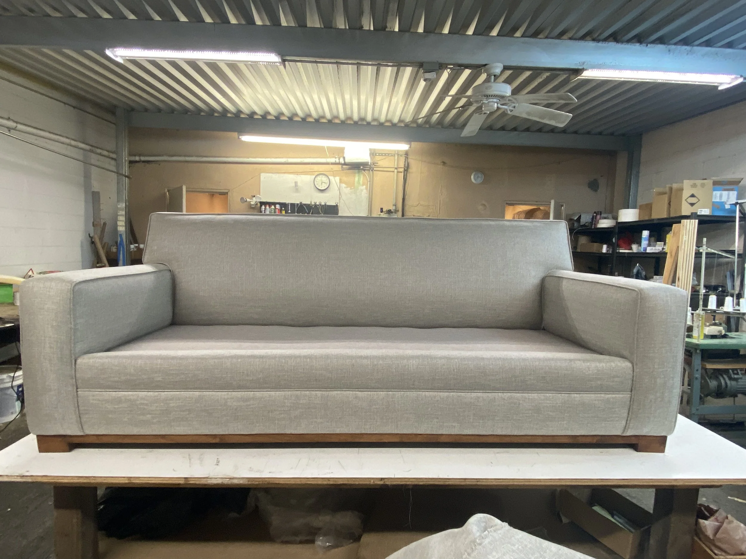 Modern sofa reupholstered in grey tweed fabric with a custom made wooden base.