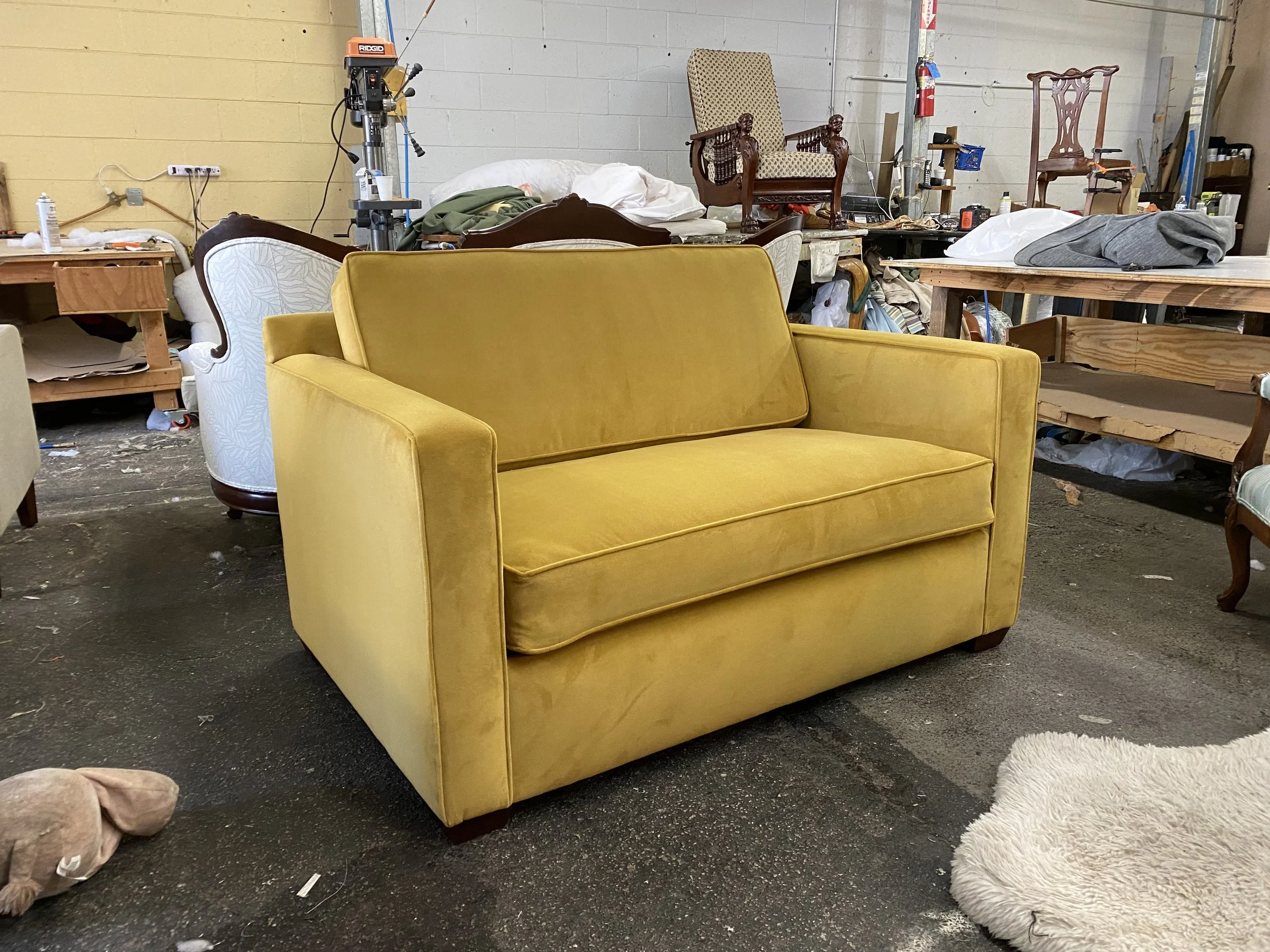 Wide arm chair reupholstered in a yellow velvet fabric with piping including high resilient foam. 