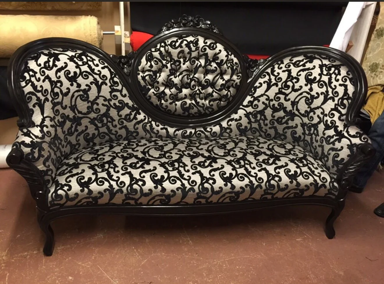 Antique sofa for the TV show Dexter upholstered in a black and white pattern fabric, with a refinished wooden frame in black. 