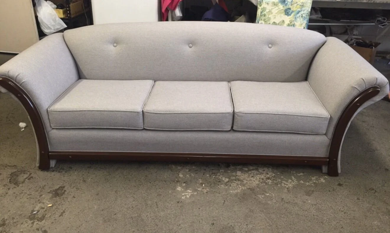 Mid-century modern loveseat upholstered in a grey performance fabric with center buttons and 3 loose seat cushions. 