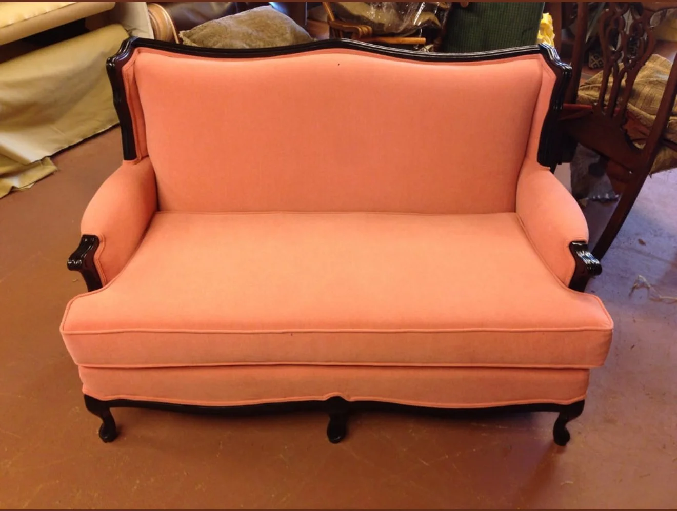 Vintage loveseat upholstered in a pink velvet with piping, double-welt and black wooden frame. 