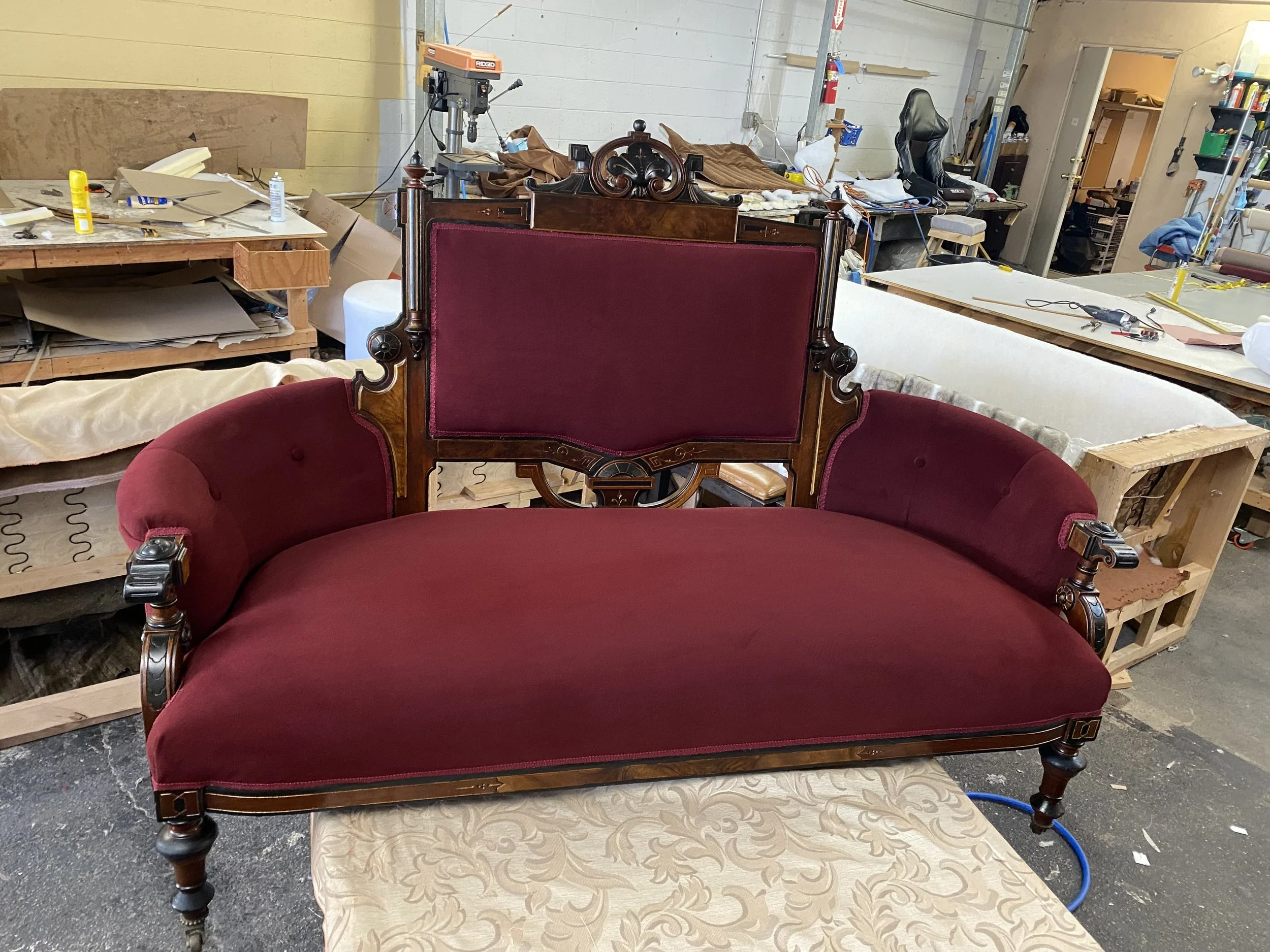Antique sofa reupholstered in a high performance red/burgundy velvet. This sofa has coil springs which have been re-tied as well as new foam for strength and comfort. The wood has been touched up and the frame has been tightened. 