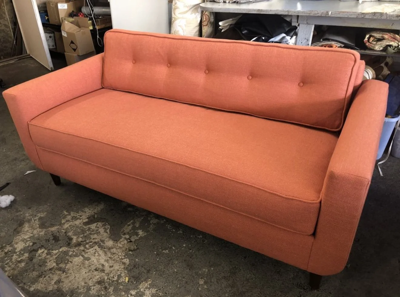 Mid century loveseat upholstered in a pink woven fabric with buttons and loose cushions. 