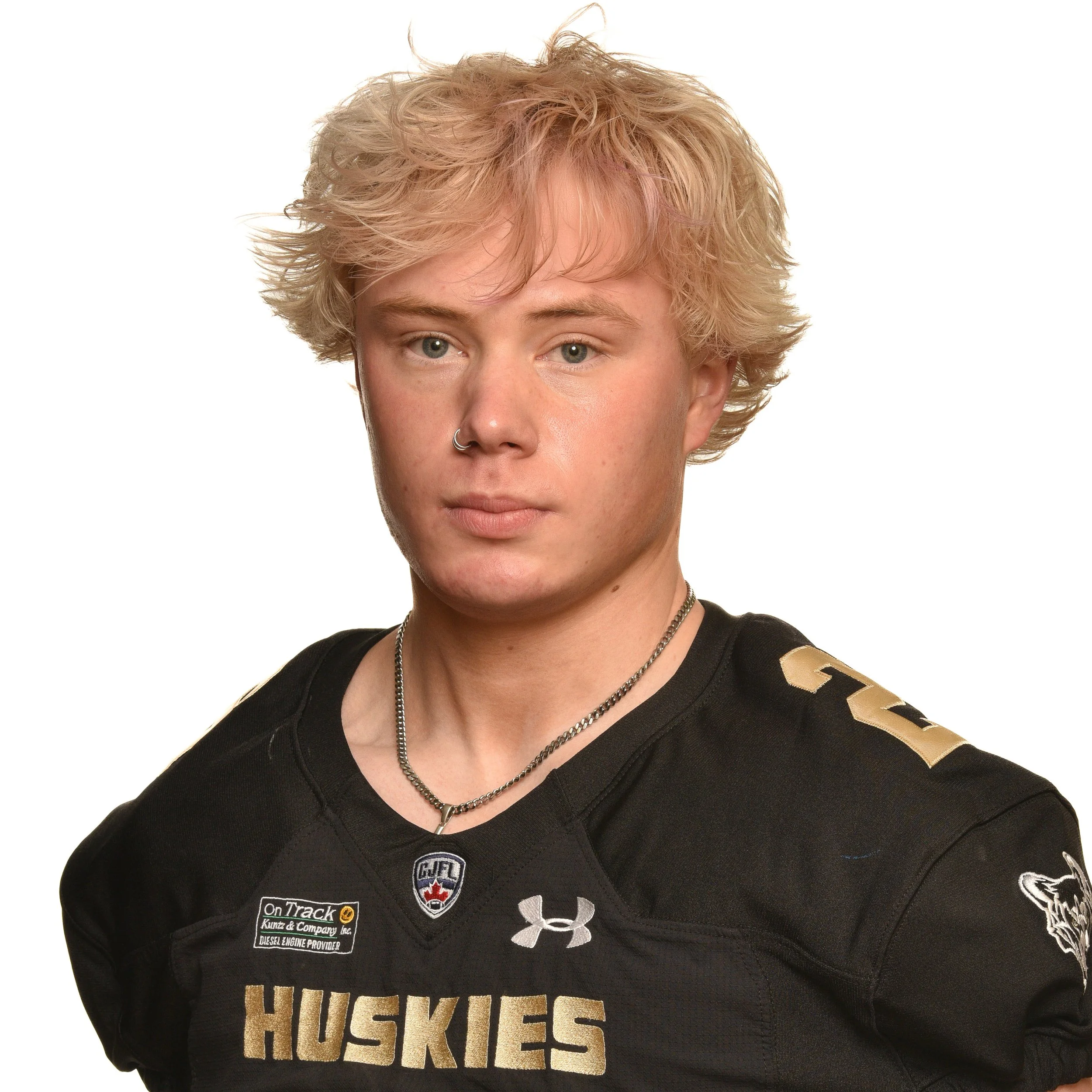 A young man with blonde hair wearing a black football uniform with the word 'Huskies' and the number 56 on it, standing against a white background.