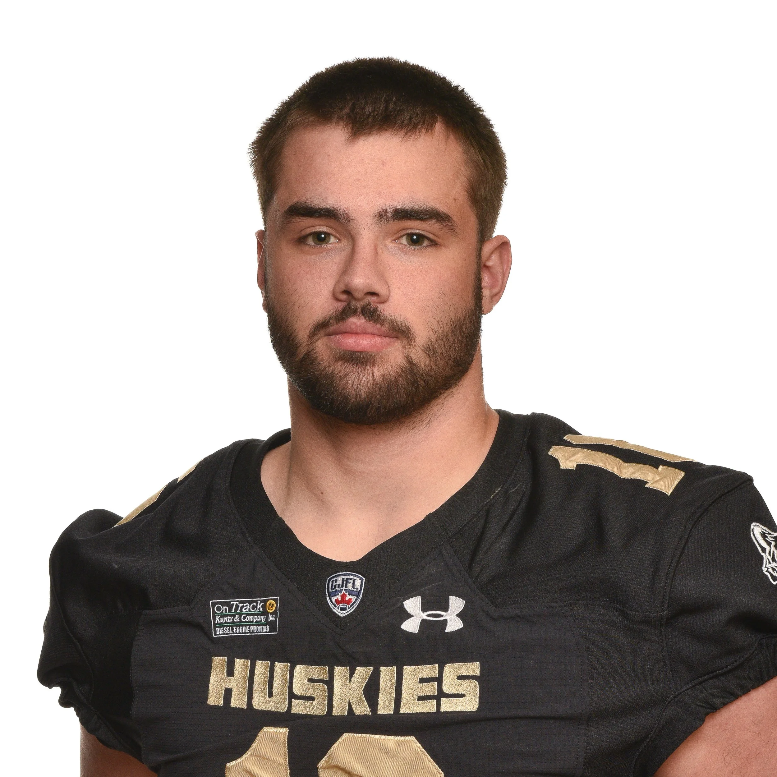 Young male football player in a black jersey with 'Huskies' written on it, standing against a colorful digital background.