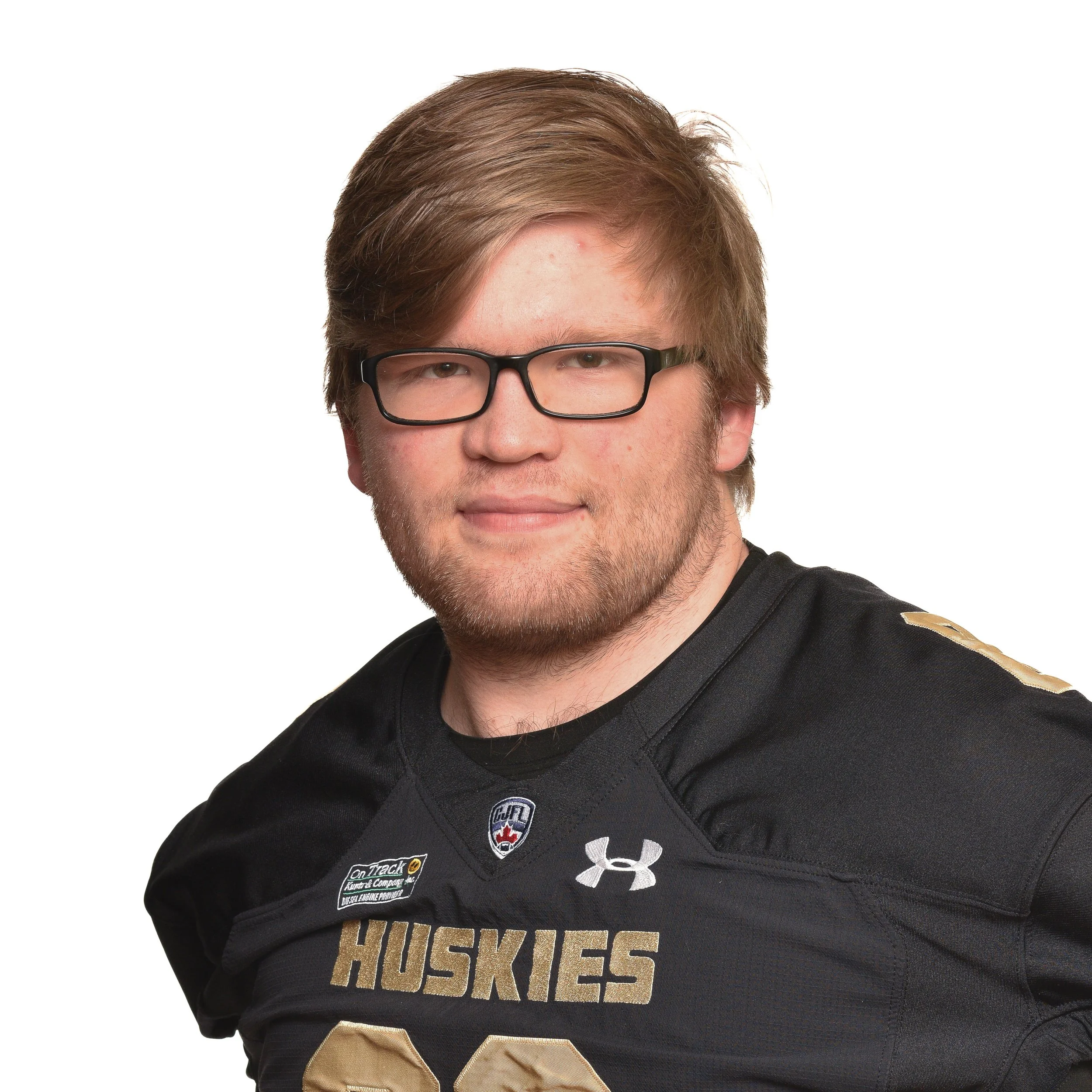 Portrait of a young man with glasses, light brown hair, and a short beard, wearing a black sports jersey with various logos.