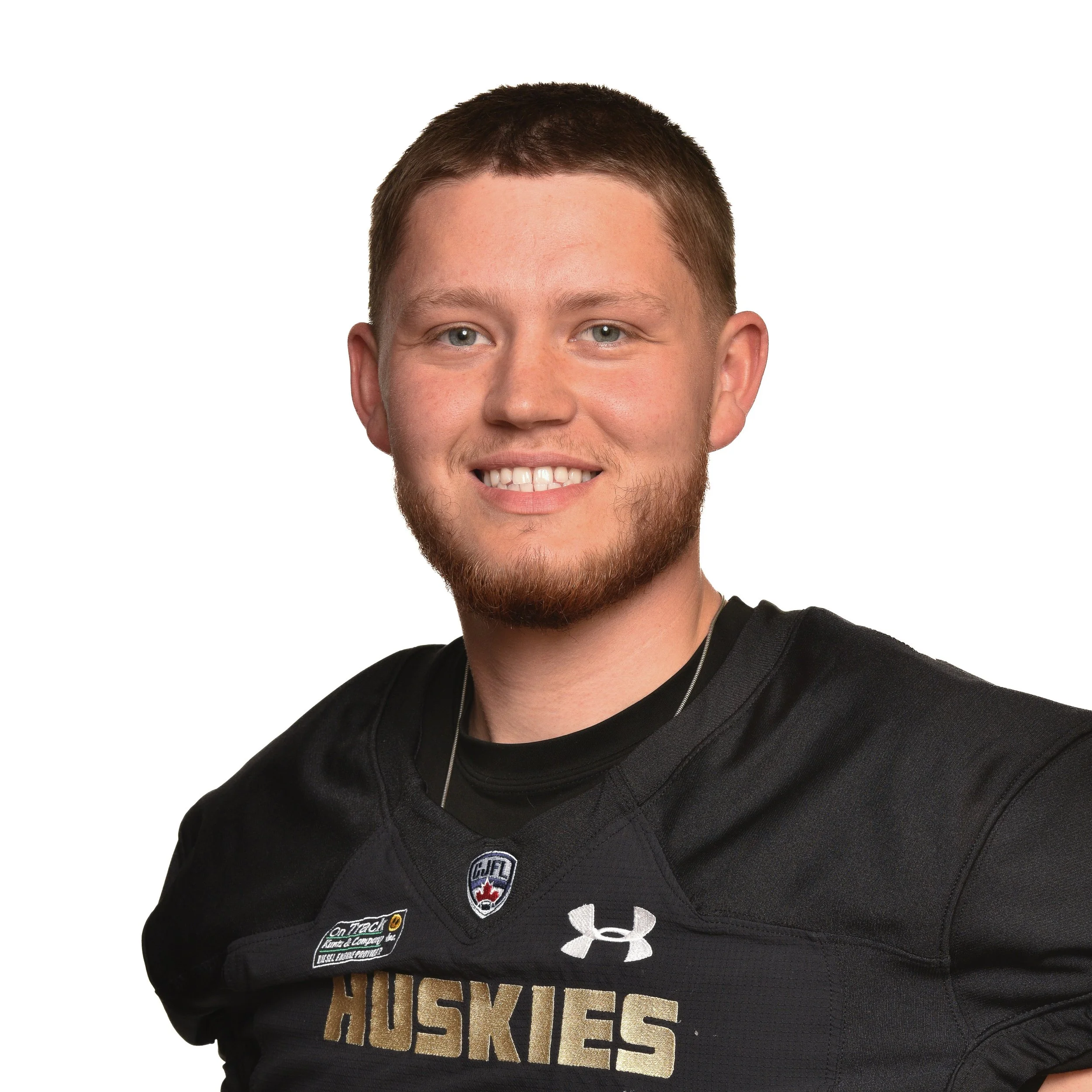 A young man wearing a black football uniform with gold accents, displaying the number 20 and the word 'Huskies.' He has short, styled brown hair and a serious expression, standing against a plain white background.