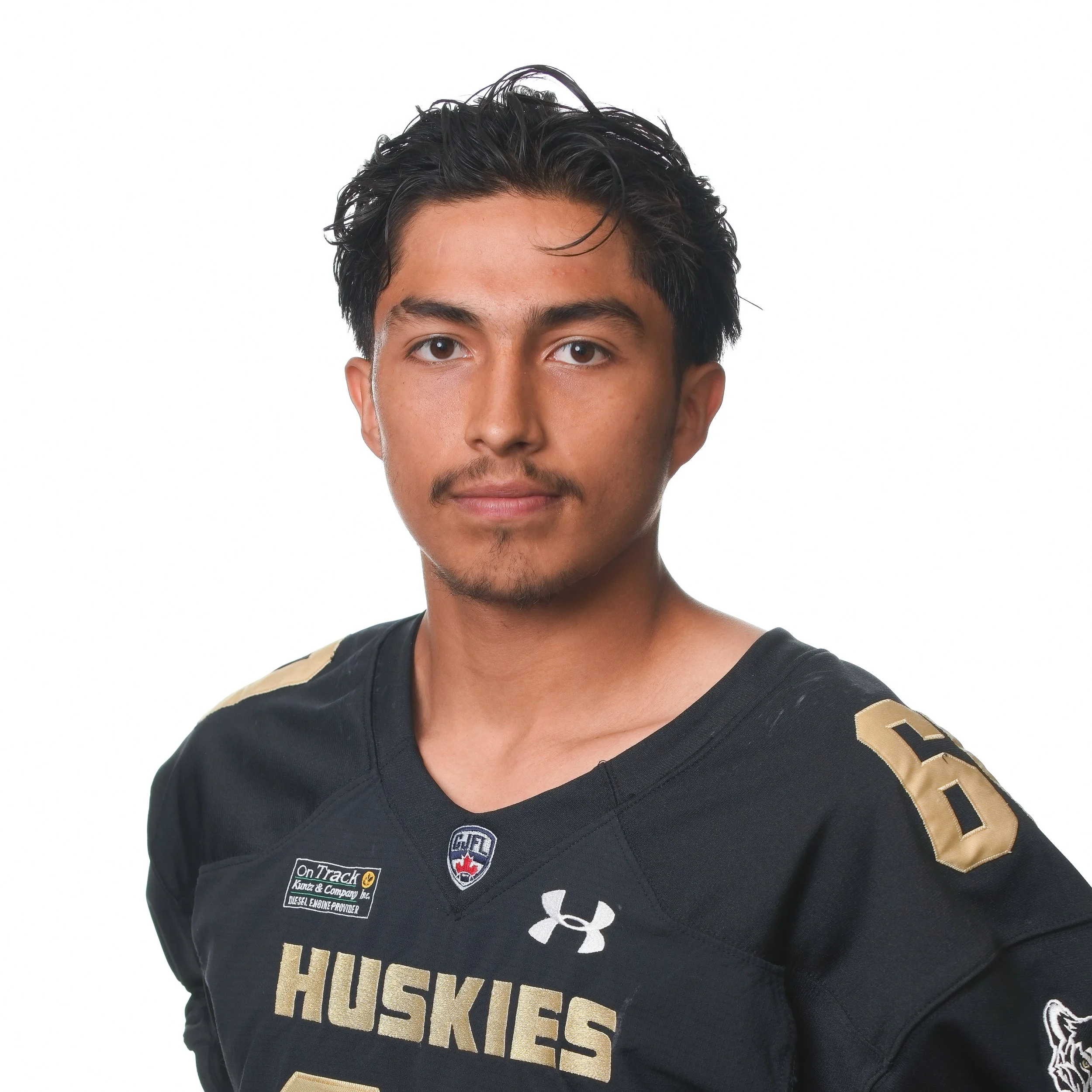 Young male football player wearing a black Huskies football uniform with the number 25, standing with arms behind his back, facing forward.