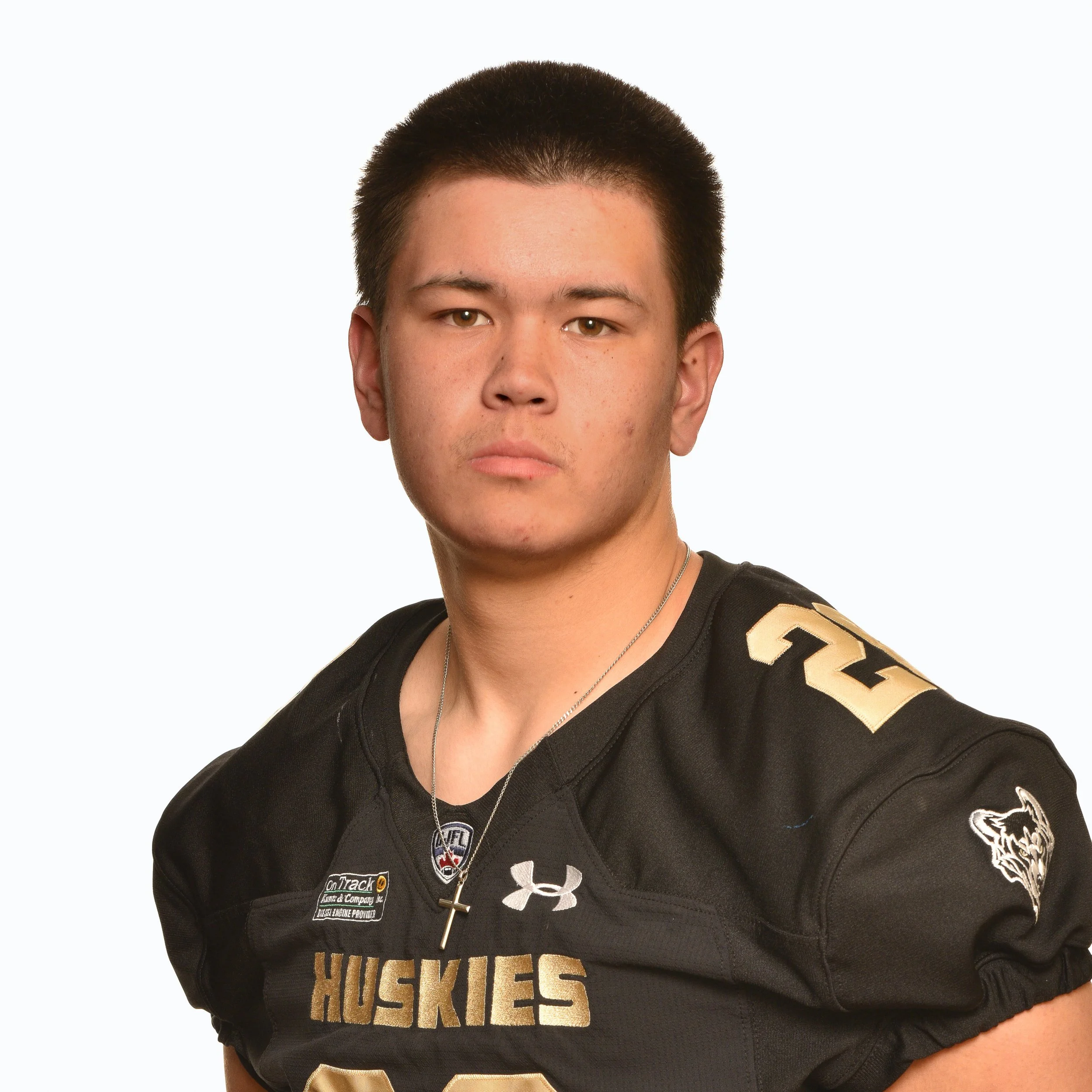 Portrait of a young male football player in a black Huskies jersey with the number 61, standing with arms behind his back against a white background.