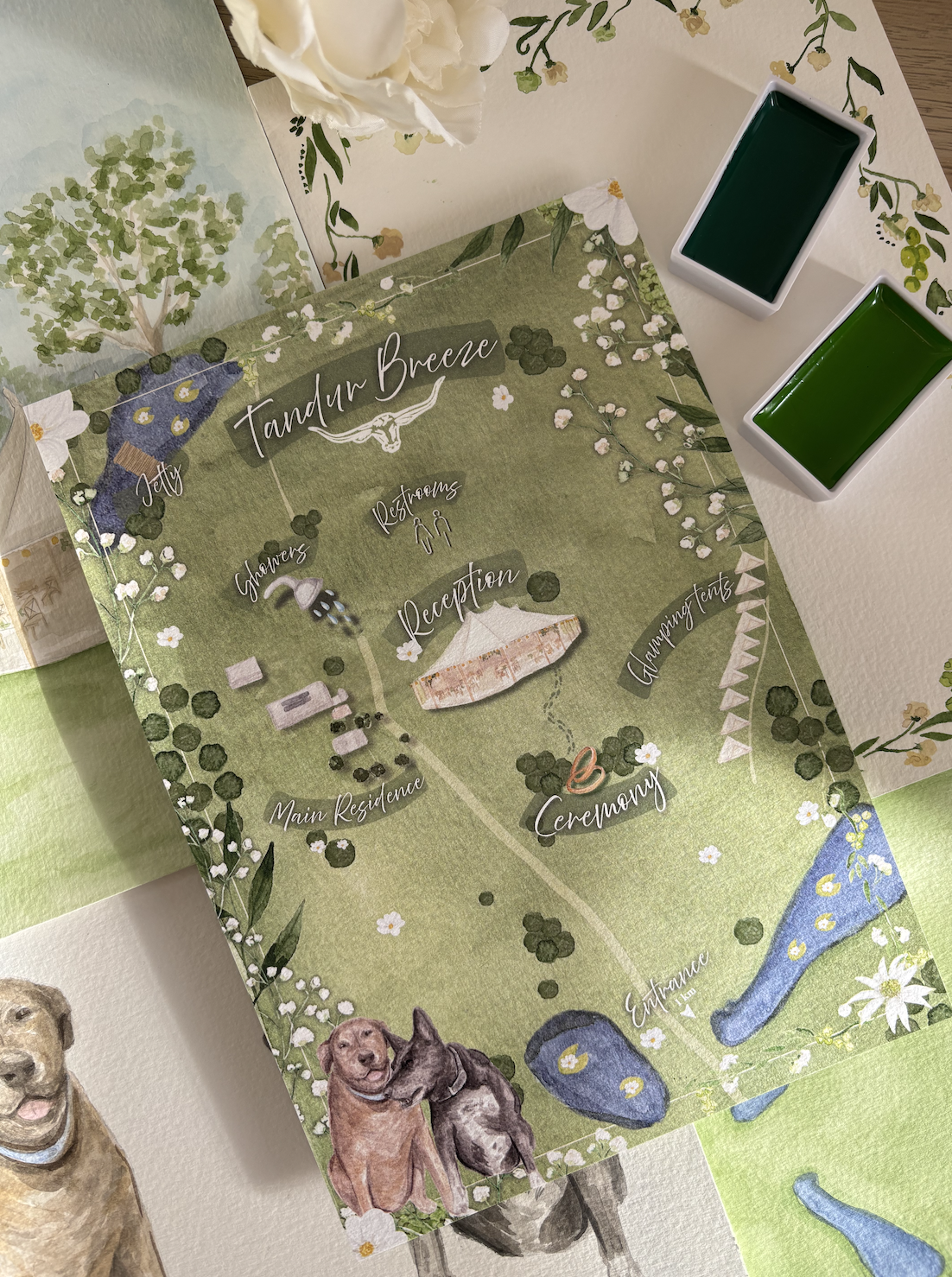 A detailed wedding site map labeled 'Tandur Breeze,' featuring areas such as 'Gates,' 'Main Residence,' 'Reception,' 'Ceremony,' 'Engagement,' 'Glamping Tents,' and 'Jetty.' The map is decorated with illustrations of trees, flowers, water, and dogs a