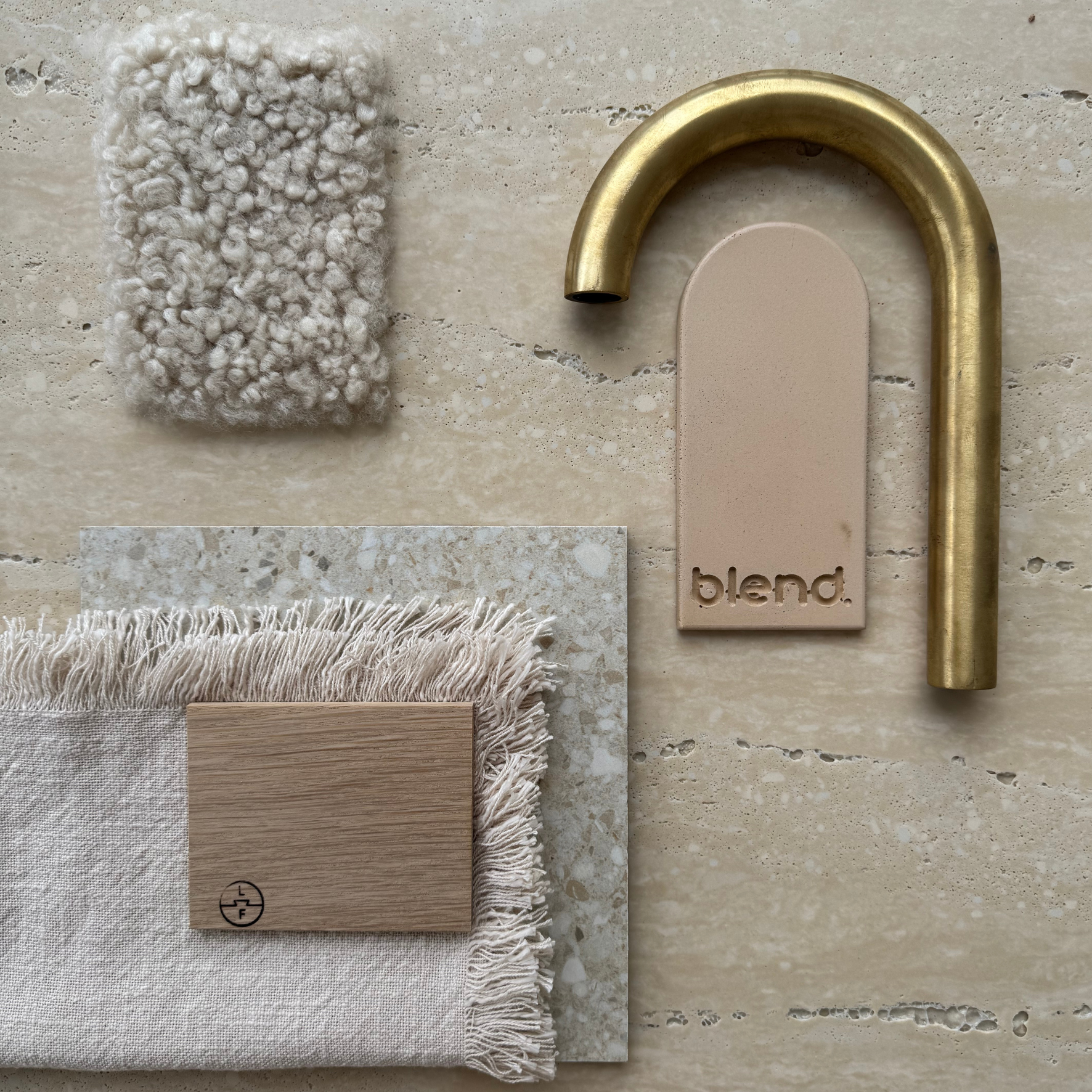 Travertine Classico Honey porcelain tile flatlay with a brushed brass tap, timber sample, neutral fabric swatches and textured beige materials.
