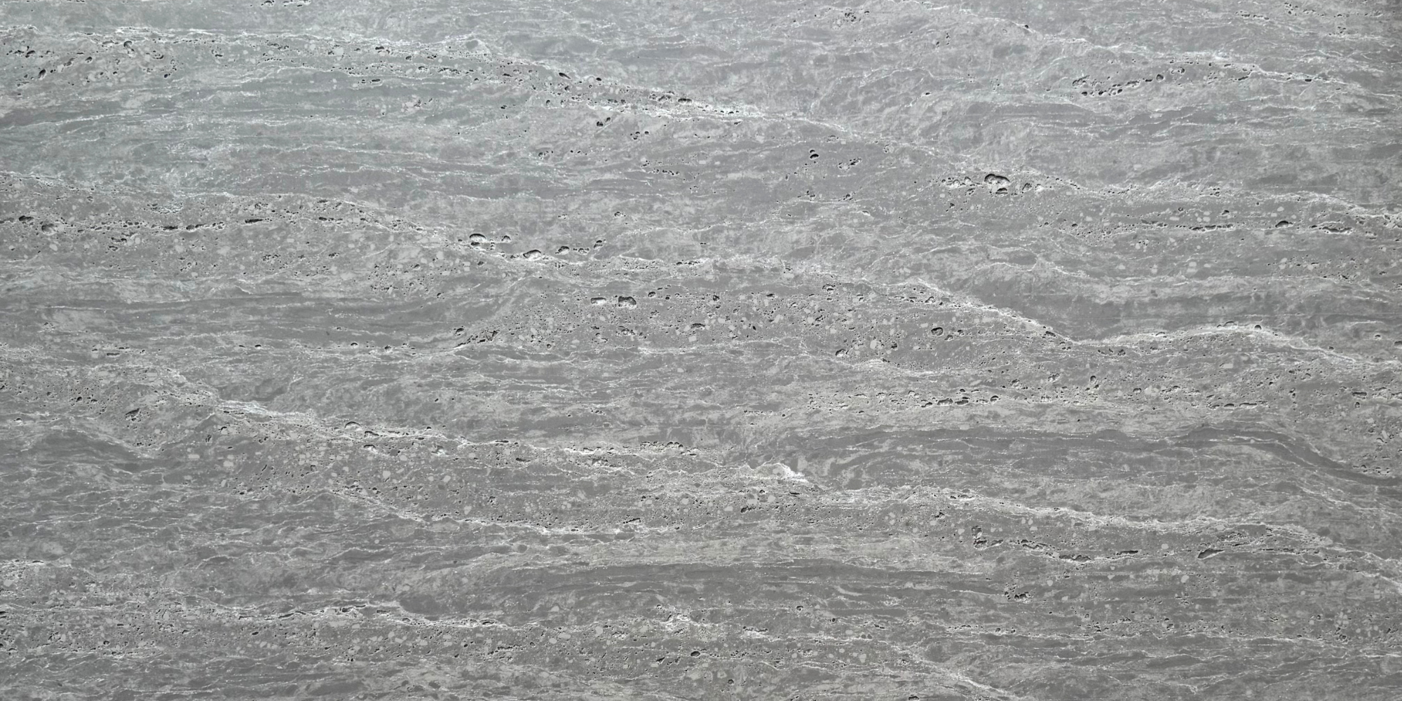 Close-up of Travertine Classico Ash grey travertine-look porcelain tile showing layered horizontal veining, subtle white streaks and distinctive surface pitting.