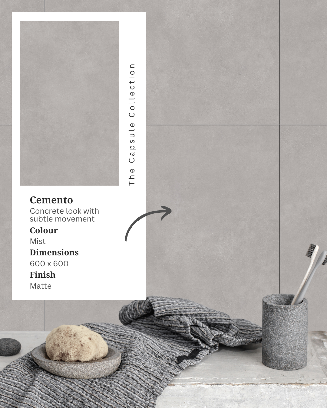 Bathroom display featuring Cemento Mist grey concrete-look porcelain wall tiles, textured grey towels, a toothbrush holder and an inset product information card.