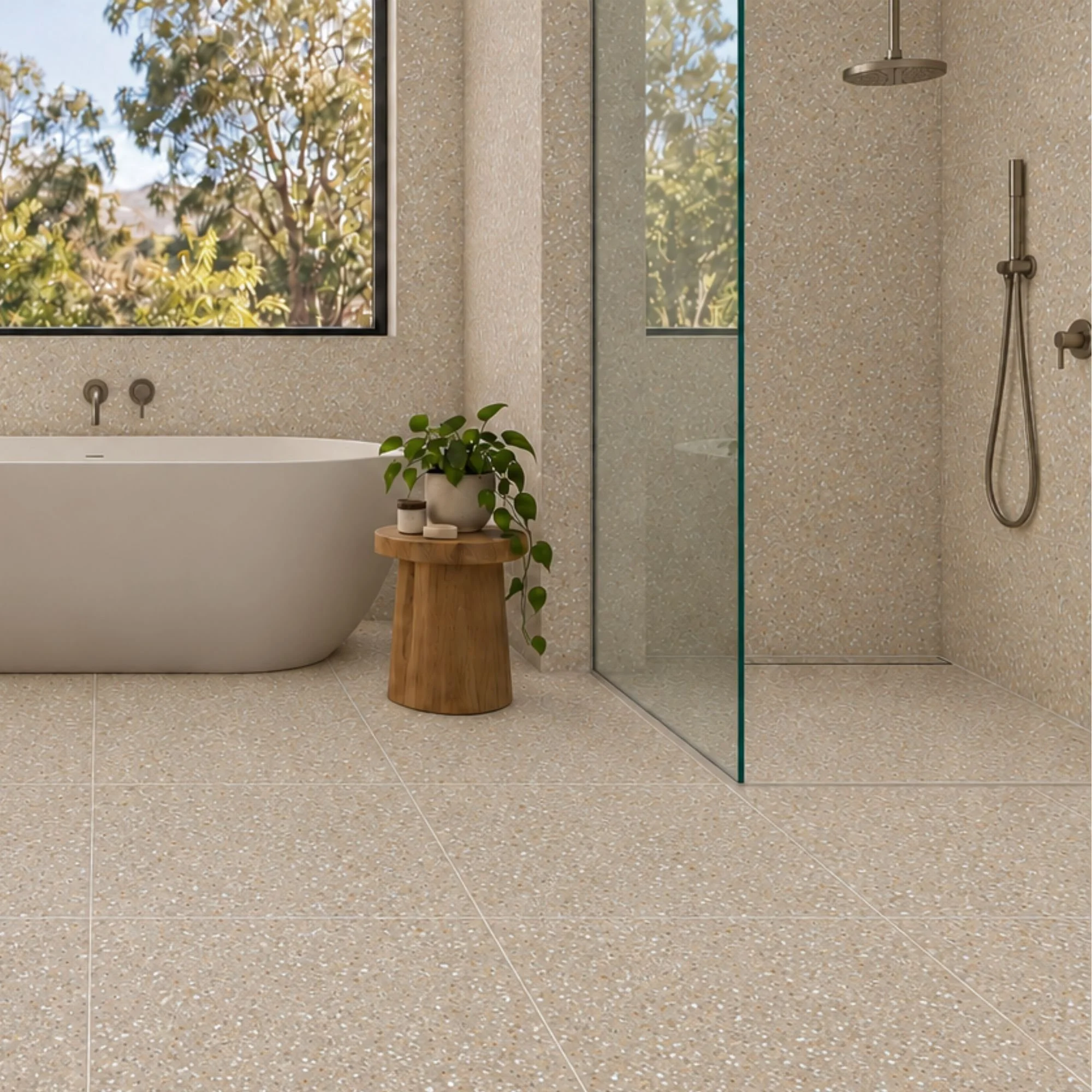 Modern bathroom featuring Terrazzo Earth beige terrazzo-look porcelain floor and wall tiles, a freestanding white bathtub, glass shower screen and timber stool.