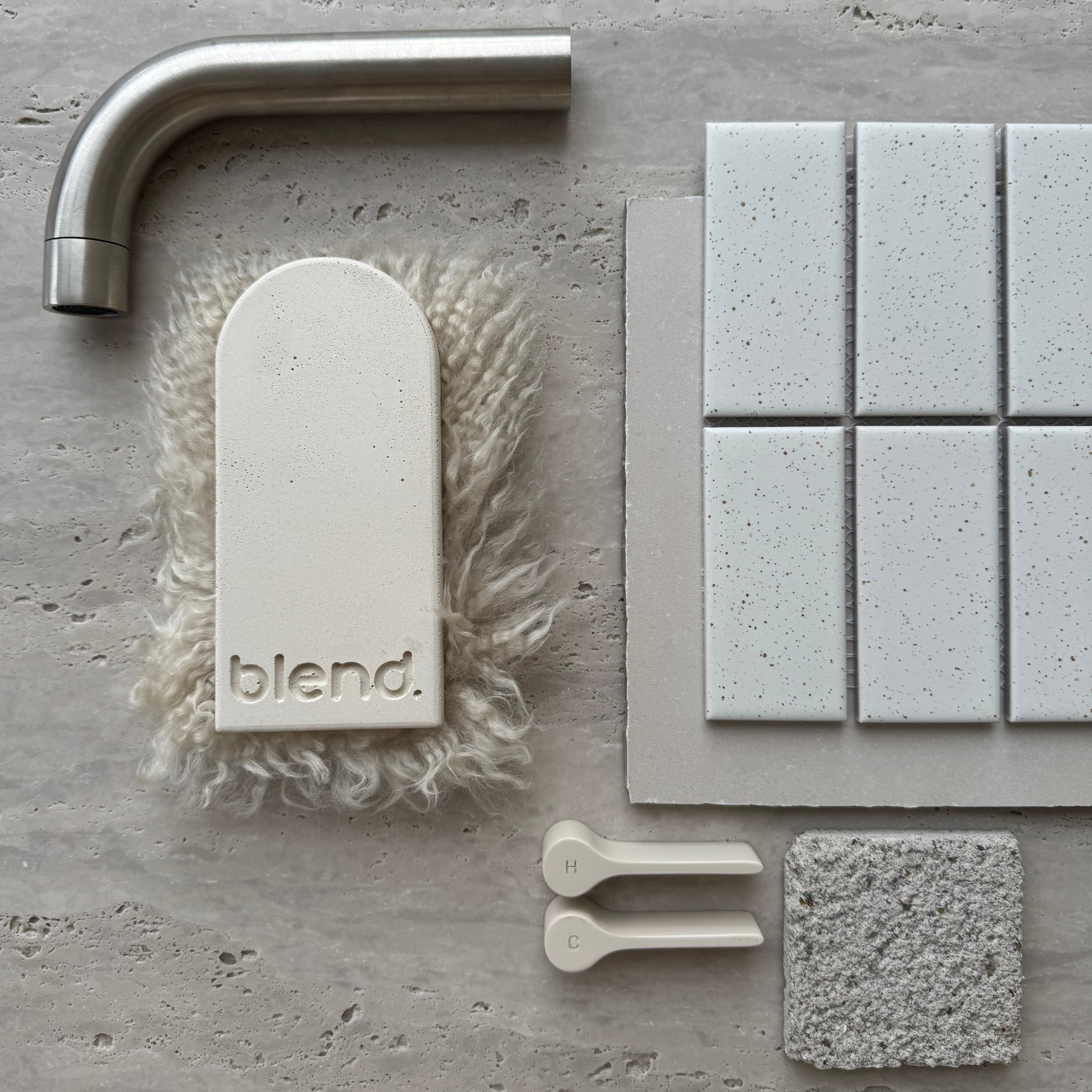 Travertine Classico Stone porcelain tile material flatlay featuring brushed metal tapware, off-white mosaic samples, textured fabric and neutral finish selections.