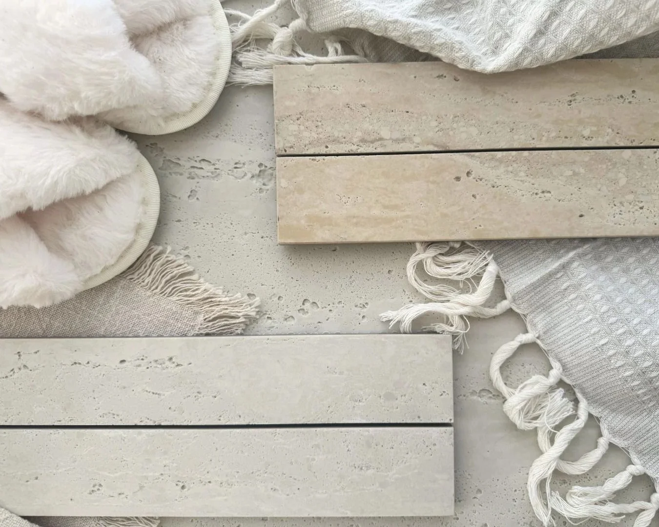 Travertine Classico Linea Linen porcelain mosaic tile samples styled with soft cream slippers, fringed linen fabrics and pale textured materials.