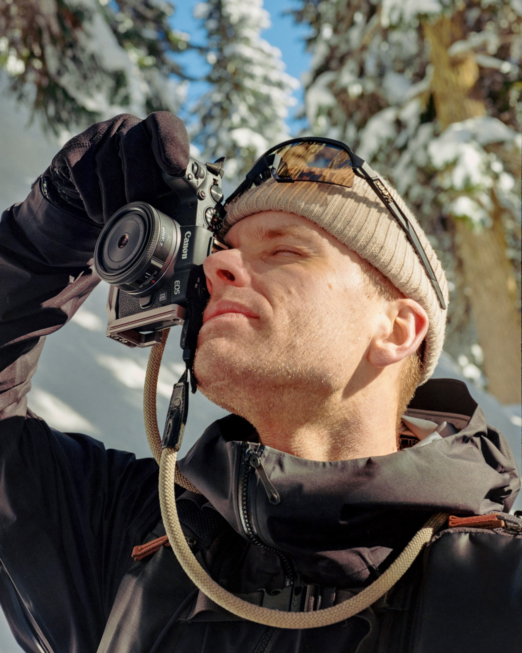Person using a Canon EOS camera outdoors in a snowy, wooded area.