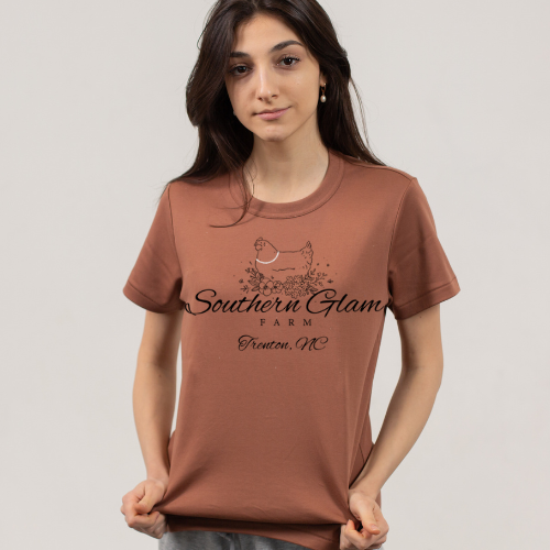 Young woman in a brown T-shirt with a chicken graphic and text that reads "Southern Glam Farm, Trenton, NC."
