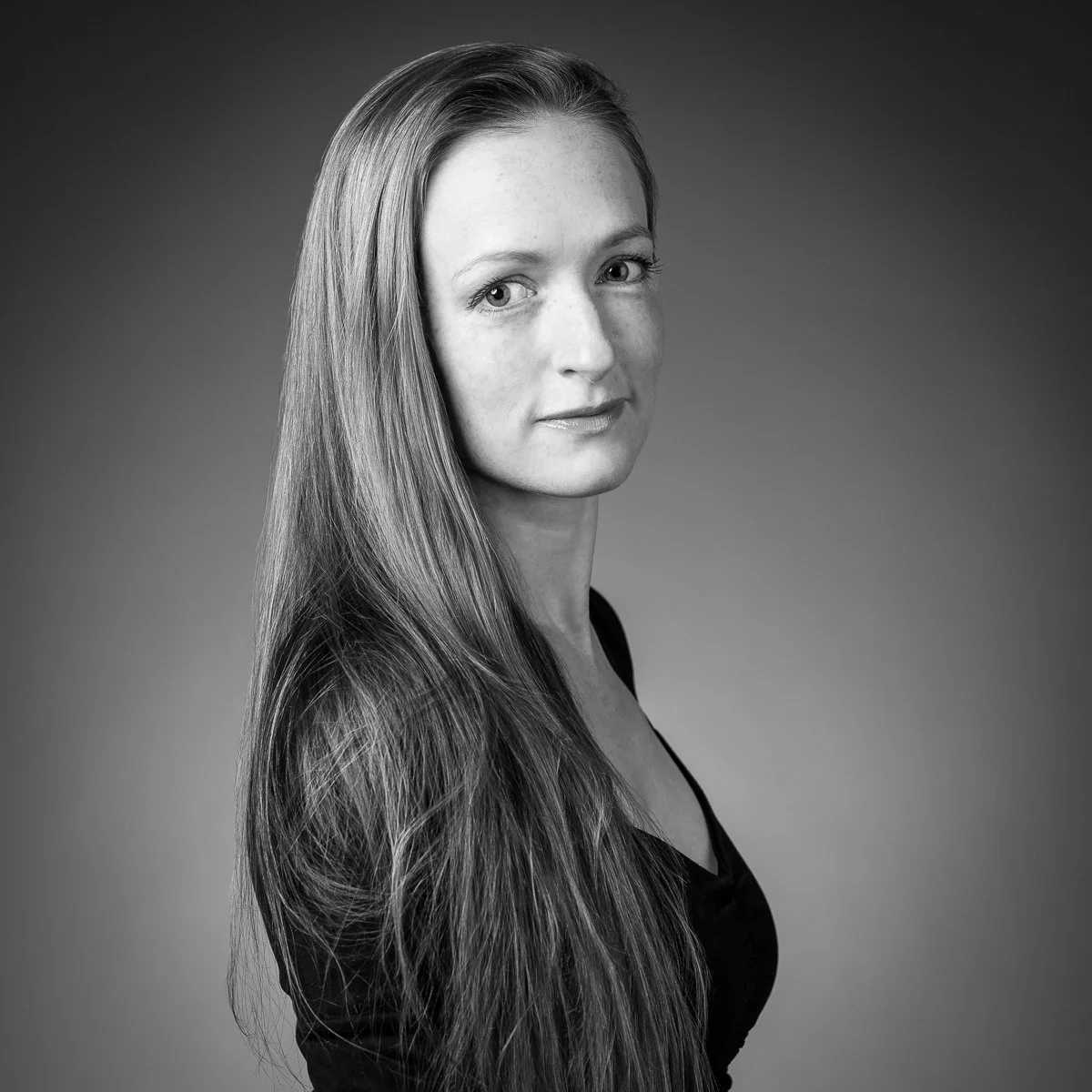 Black and white portrait of a woman with long hair, looking at the camera with a slight smile.