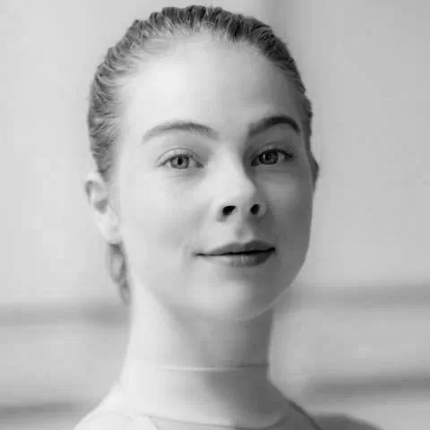 Black and white portrait of a young woman with her hair tied back, looking at the camera.