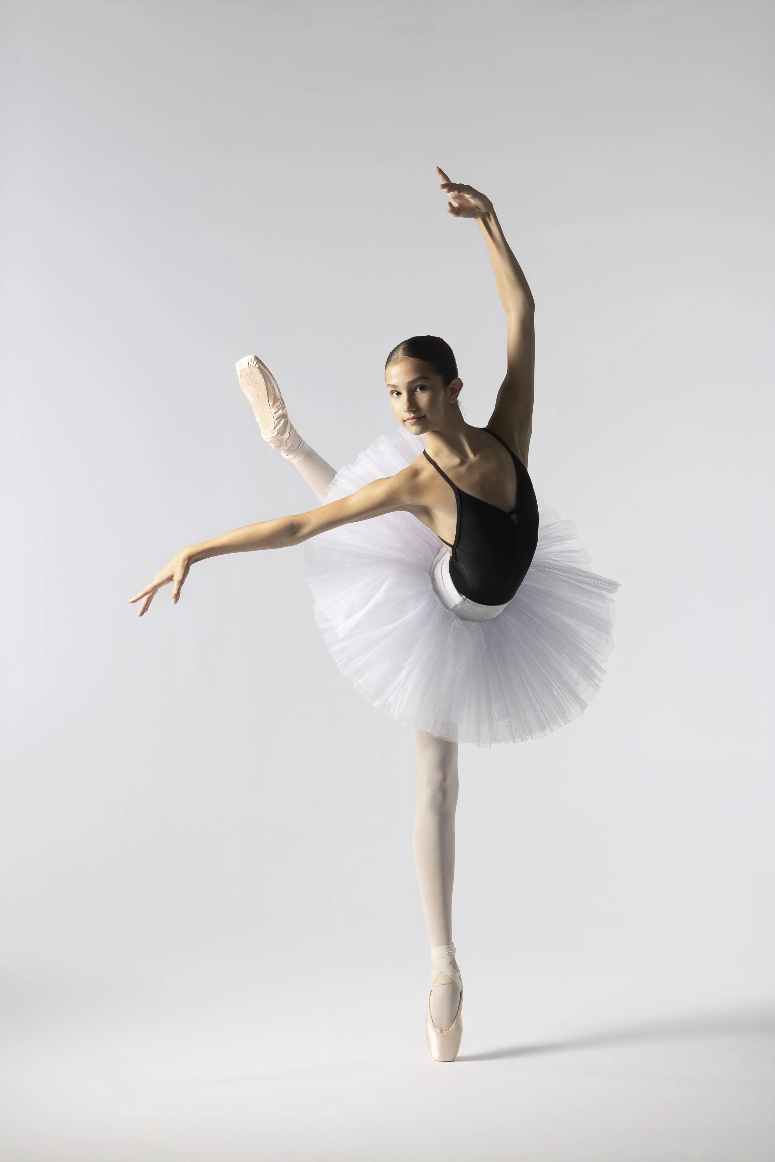 A ballet dancer practicing in a dance studio with large windows and dark curtains.