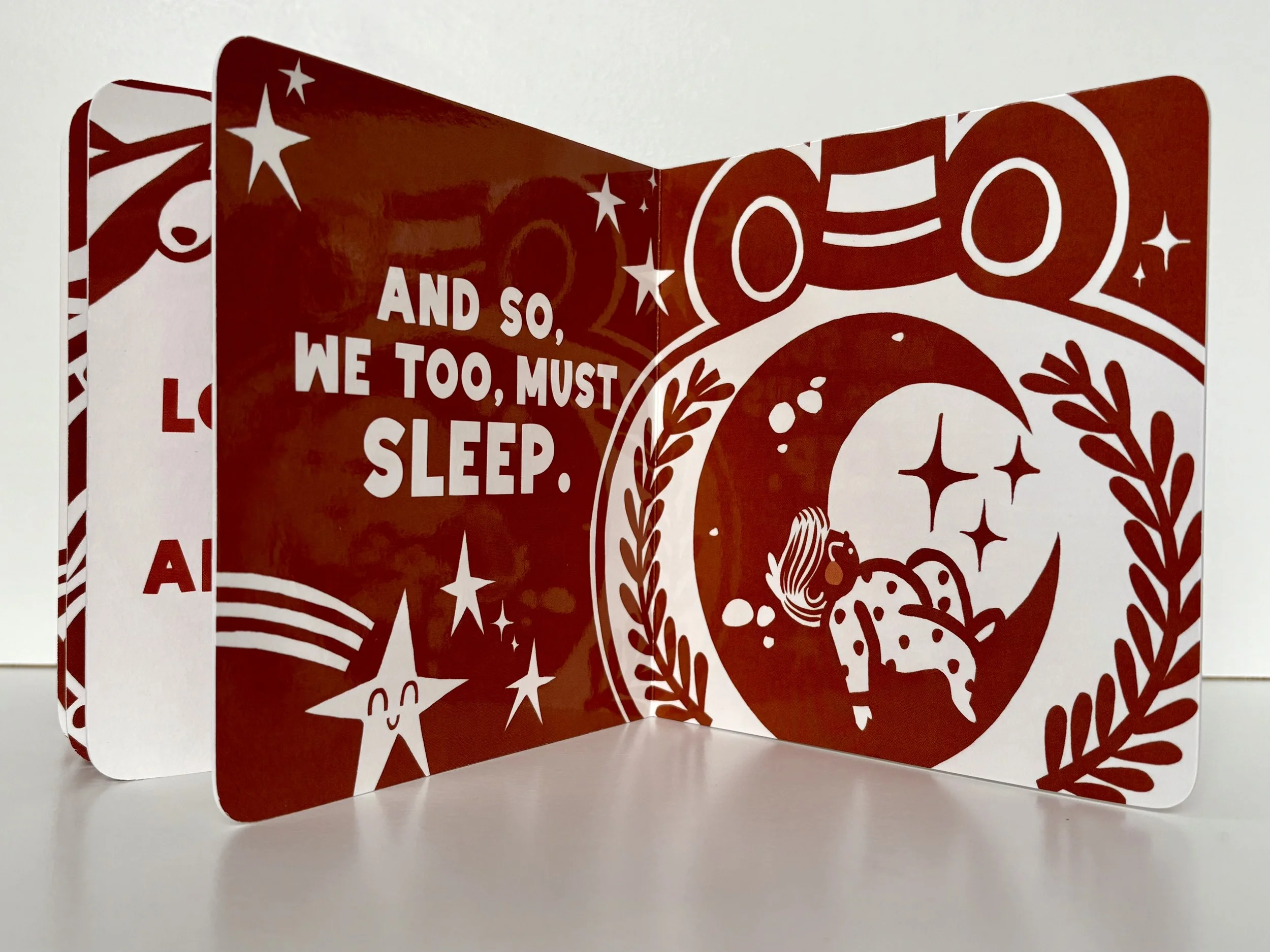 Page from high-contrast book showing illustration of baby asleep in a crescent moon.