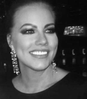Black and white photo of a smiling woman with long earrings.