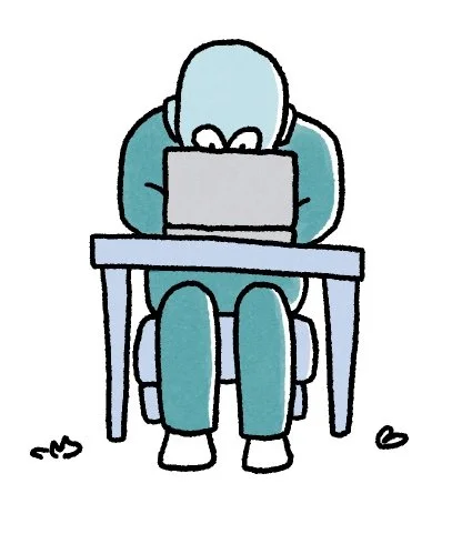A person sitting at a desk, leaning forward and using a laptop, with their head down.