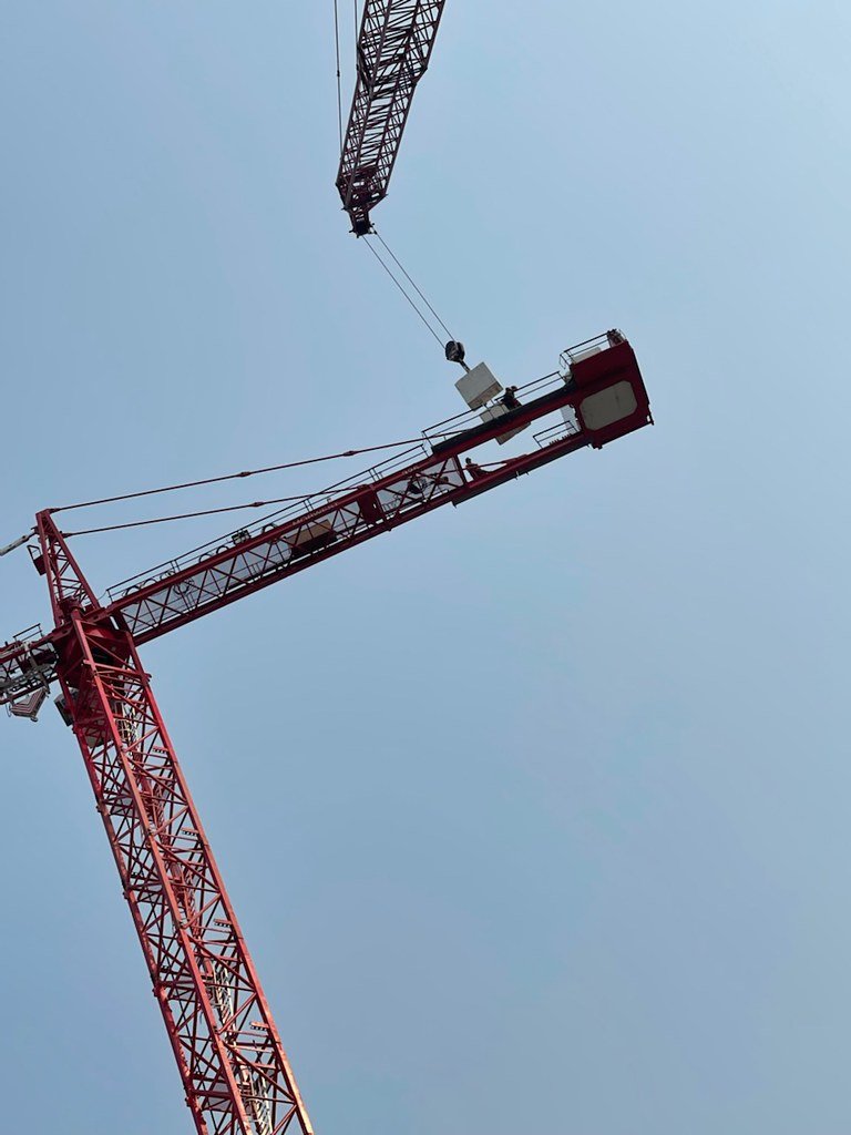 A red construction crane against a clear blue sky