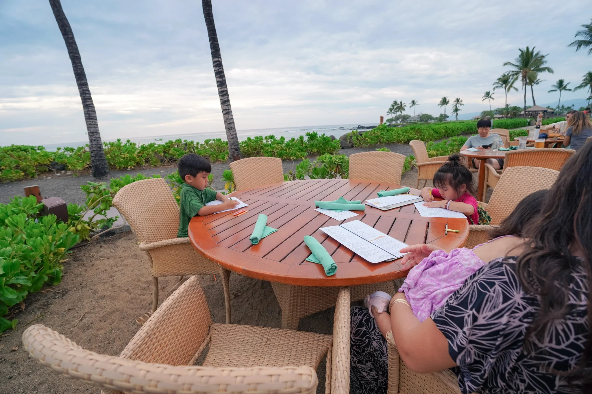 Our keiki coloring at our Hale Kai dinner table with wide ocean views behind them
