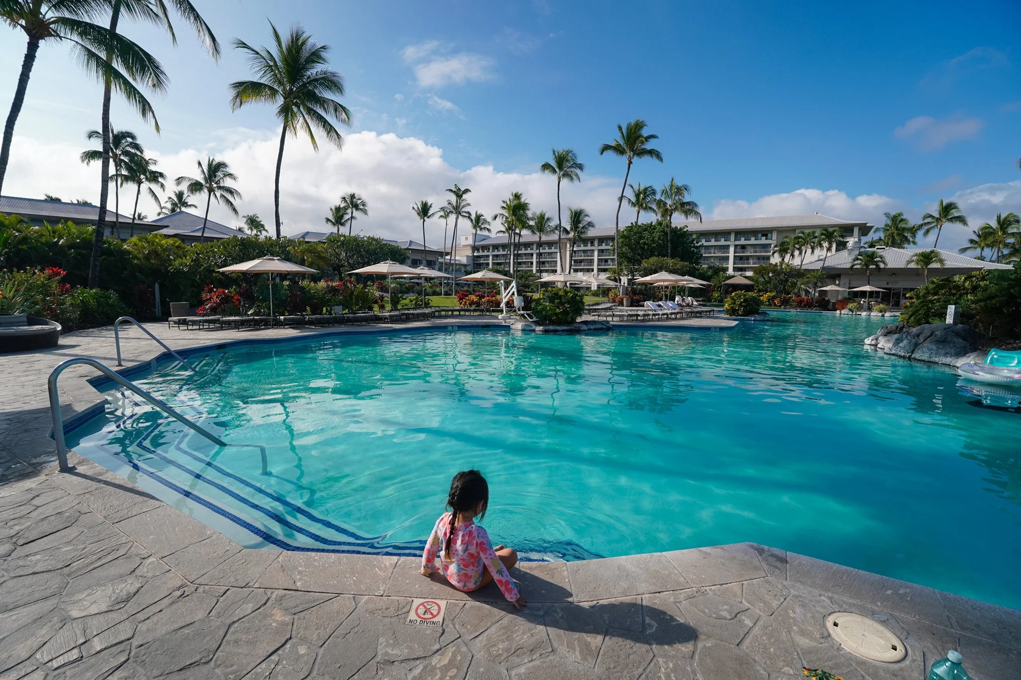 The 10,000 square foot free-form pool at the Fairmont Orchid with a child sitting on the steps