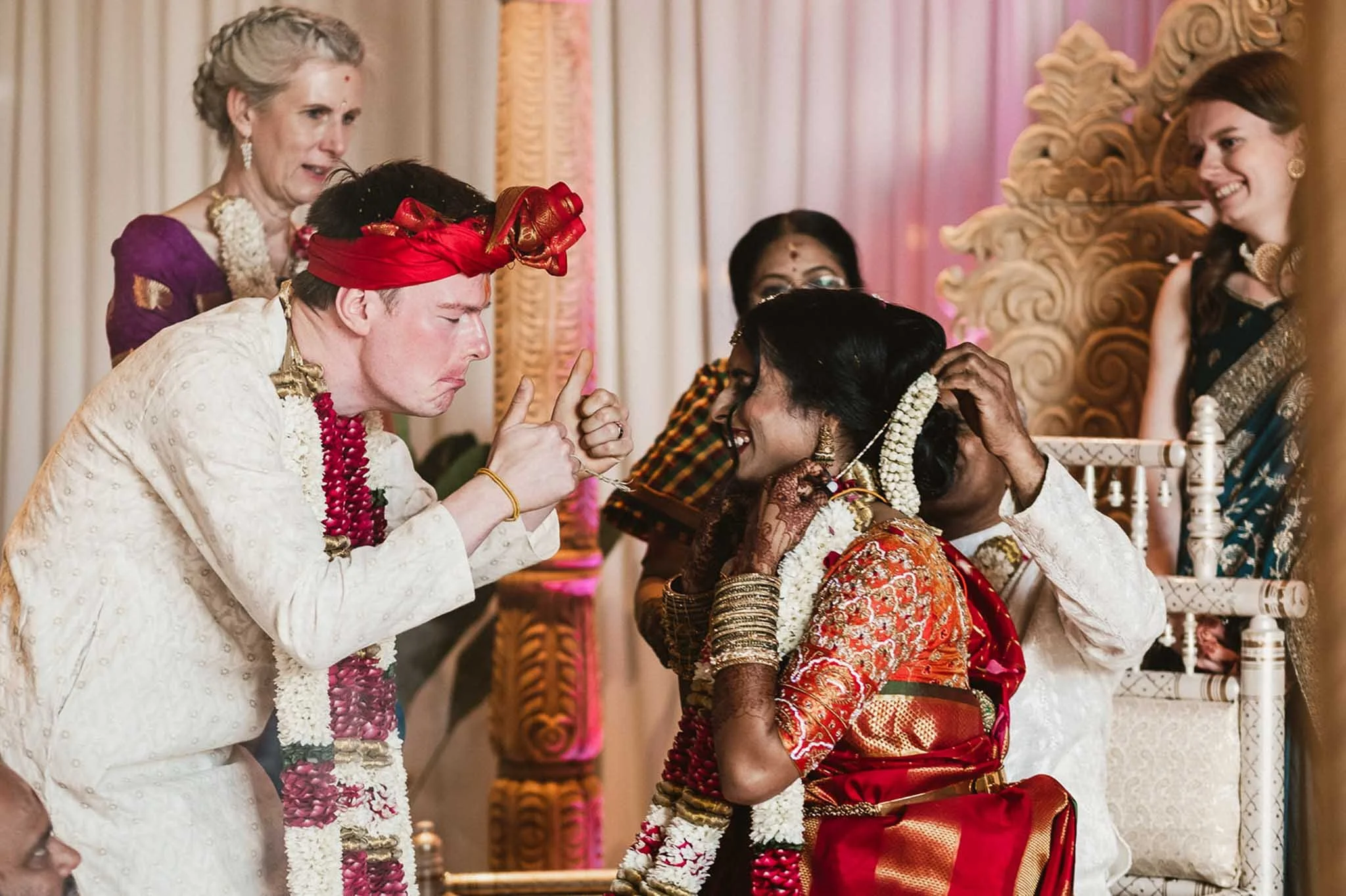 a photograph a groom giving the bride the thumbs up during their wedding ceremony