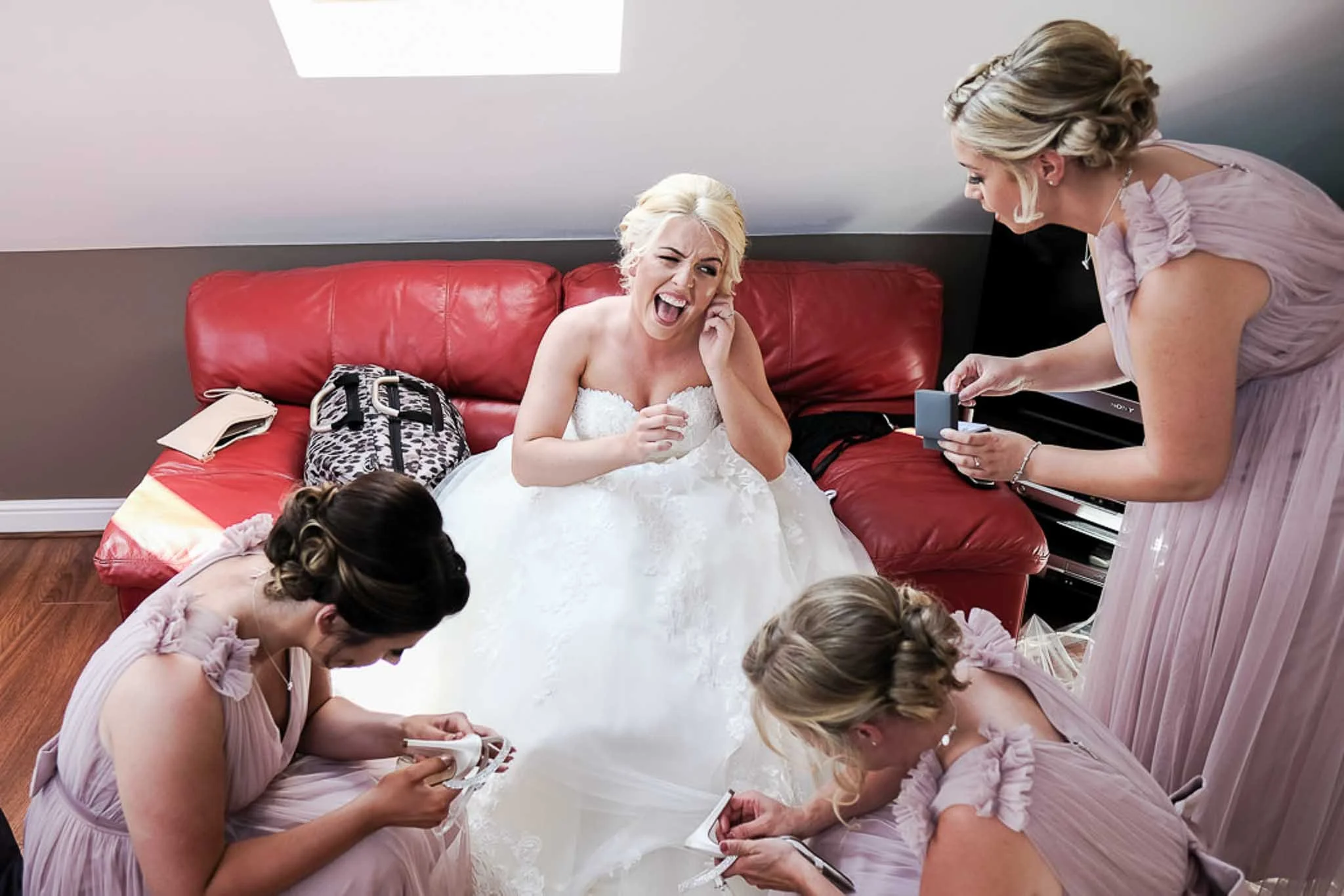 a photograph of  bride pulling a face when trying to get her ear rings in.