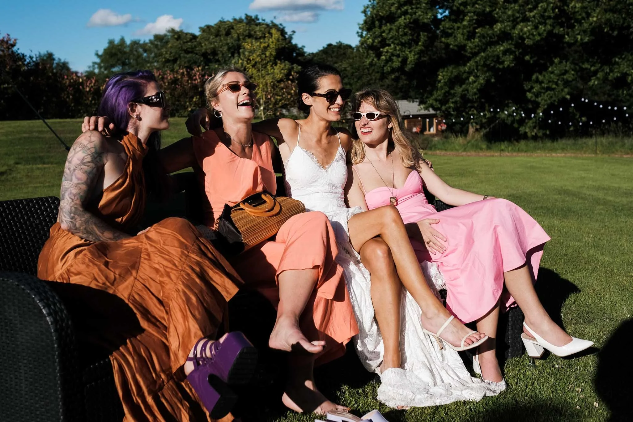 a photograph a bride and her friends chilling on a hey bale.