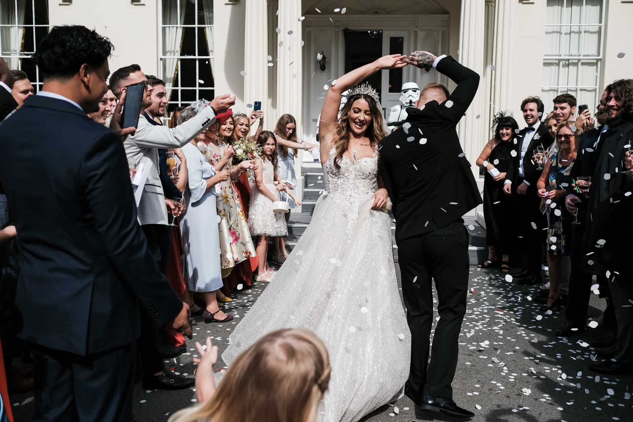 bride and groom celebrating and dancing whilst confetti is being thrown. The bride bought her dress from our bridal bouquet in Liverpool.