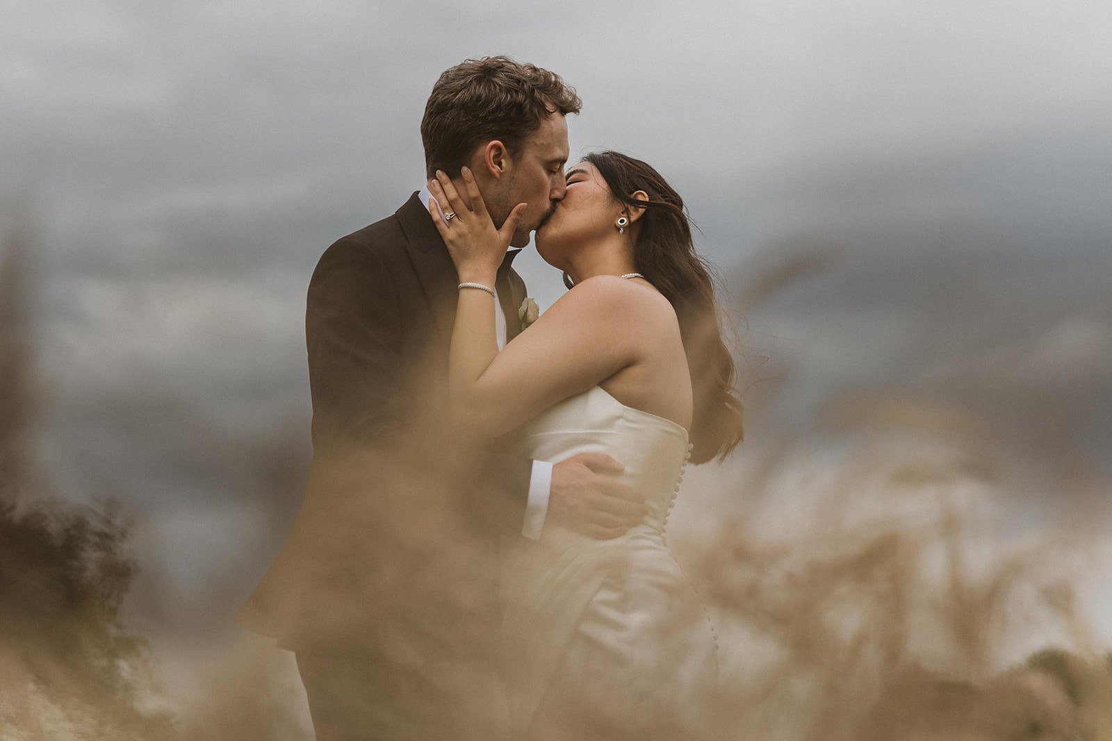 bride and groom kissing in the meadow flowers and Meols Hall in Southport, Merseyside