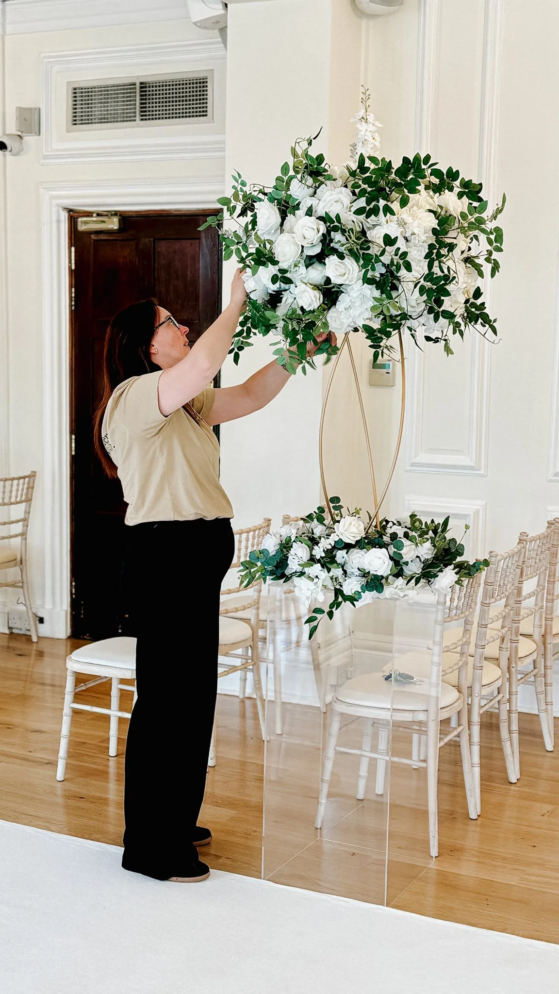A photograph showing sarah a member of the alexander wedding co team styling the wedding aisle at West Tower  in Lancashire.