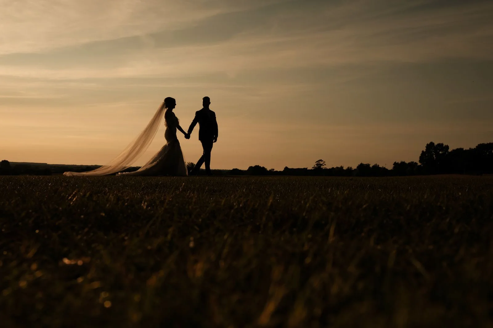 Wedding couple walking across the lawn during golden hour at West Tower, Lancashire