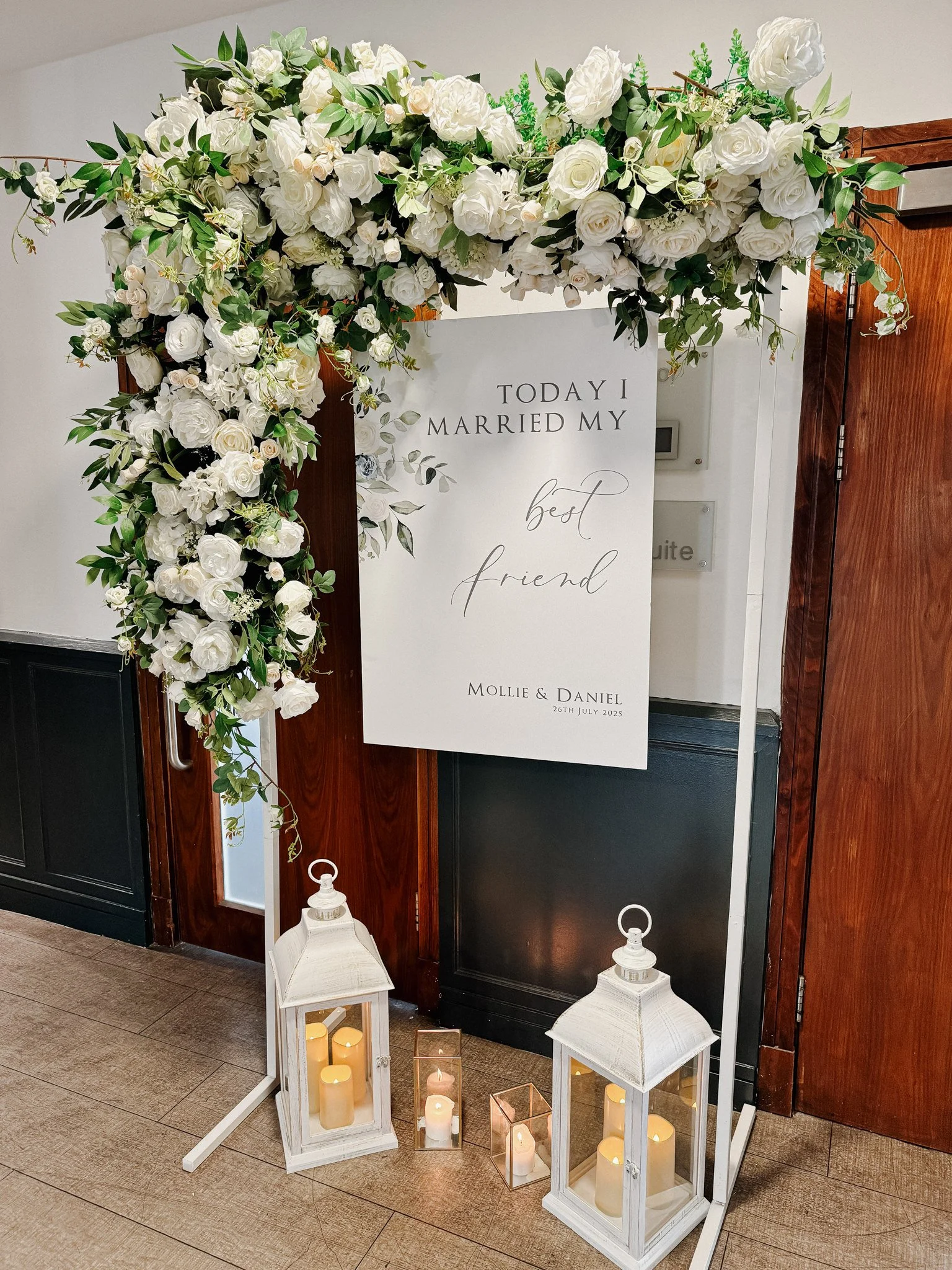 Wedding welcome sign dressed with green and white florals.