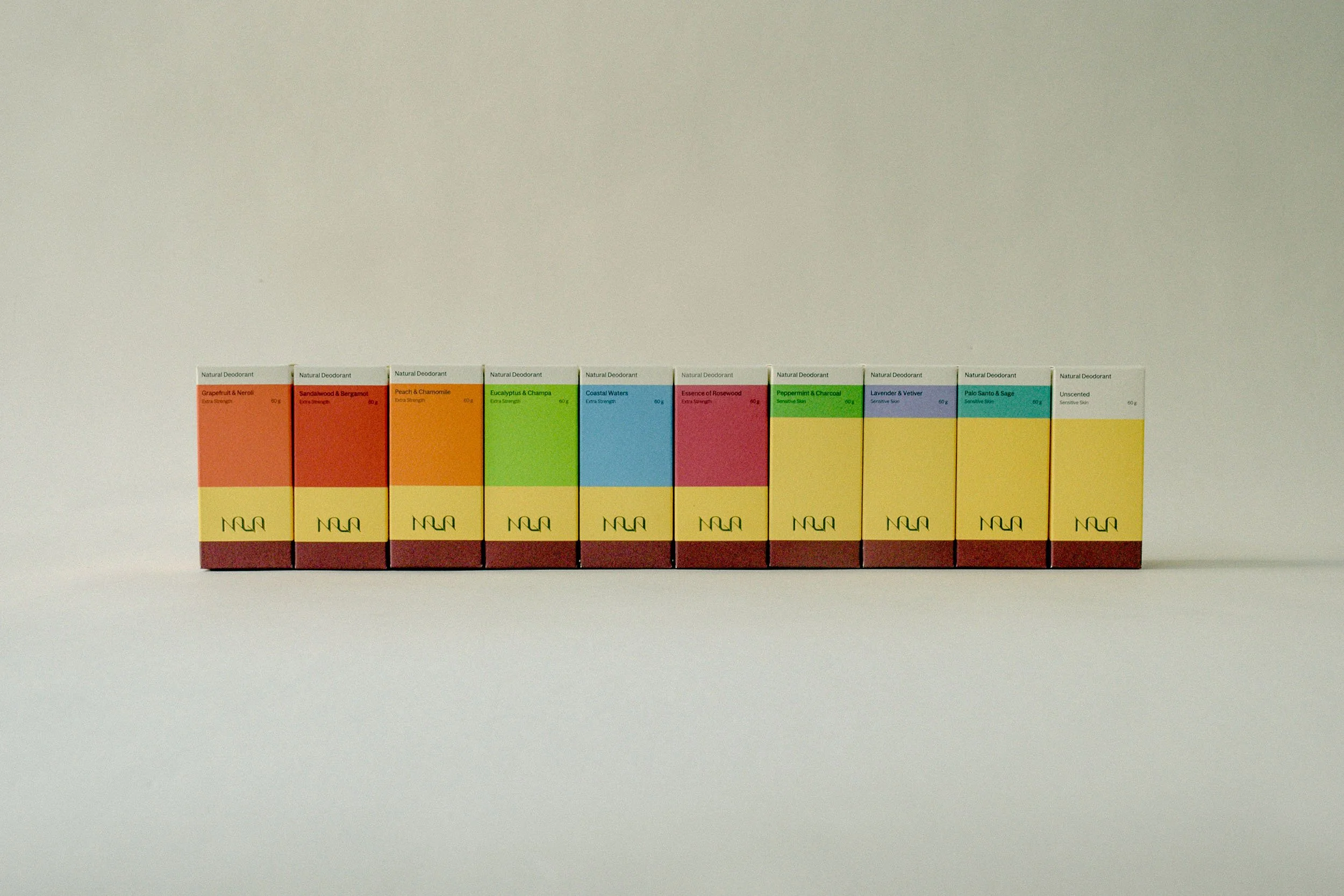 Line of assorted perfume boxes with colorful labels on a plain background.