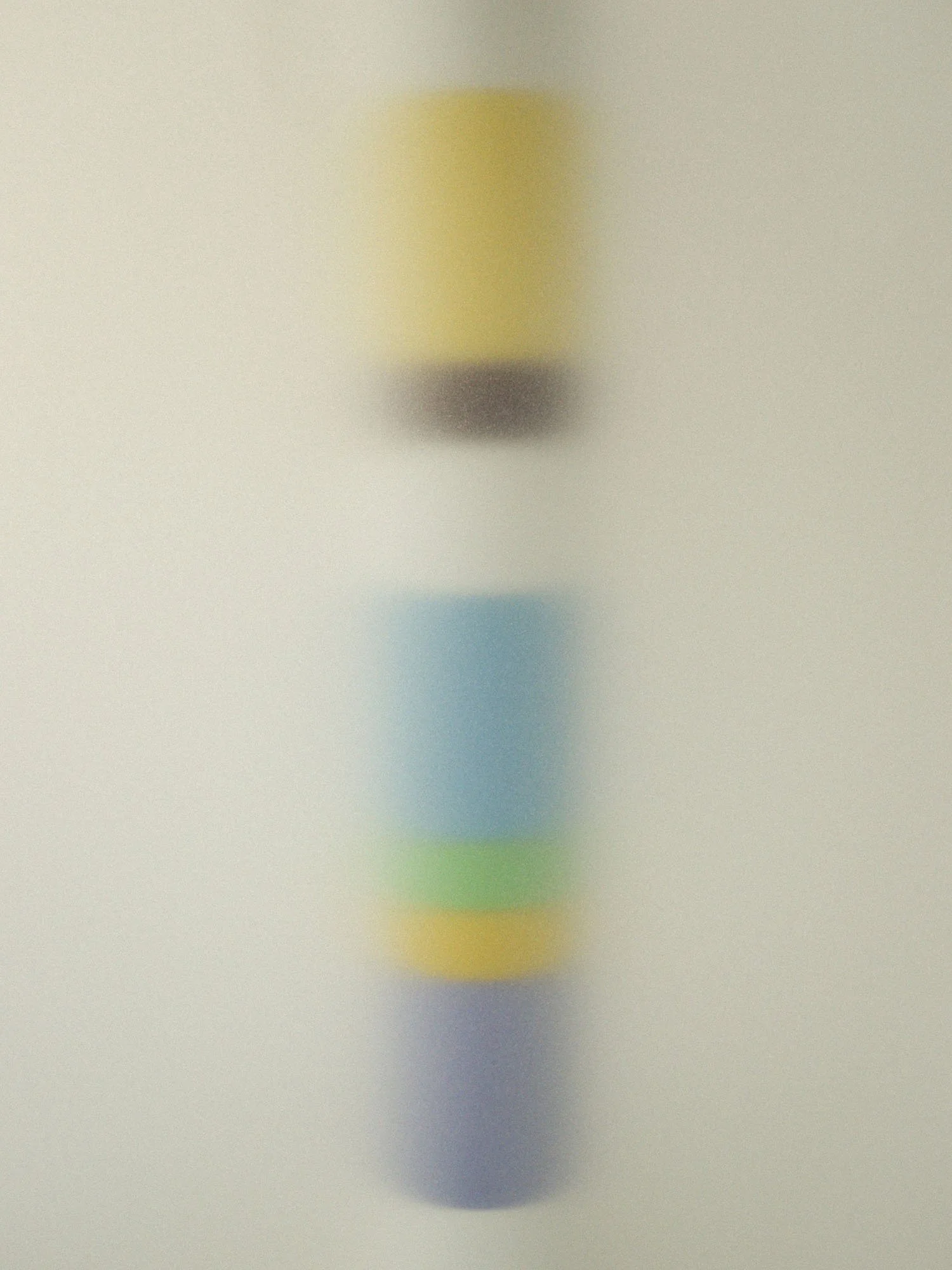 A blurred image of a yoga pose in front of a plain, light-colored background.