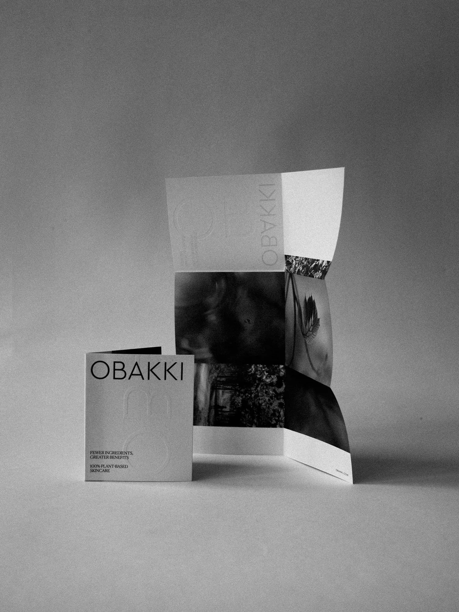 A folded brochure and a box with the brand name 'OBAKKI' on a plain surface, with the brochure standing upright and partially open, showing images and text related to skincare.