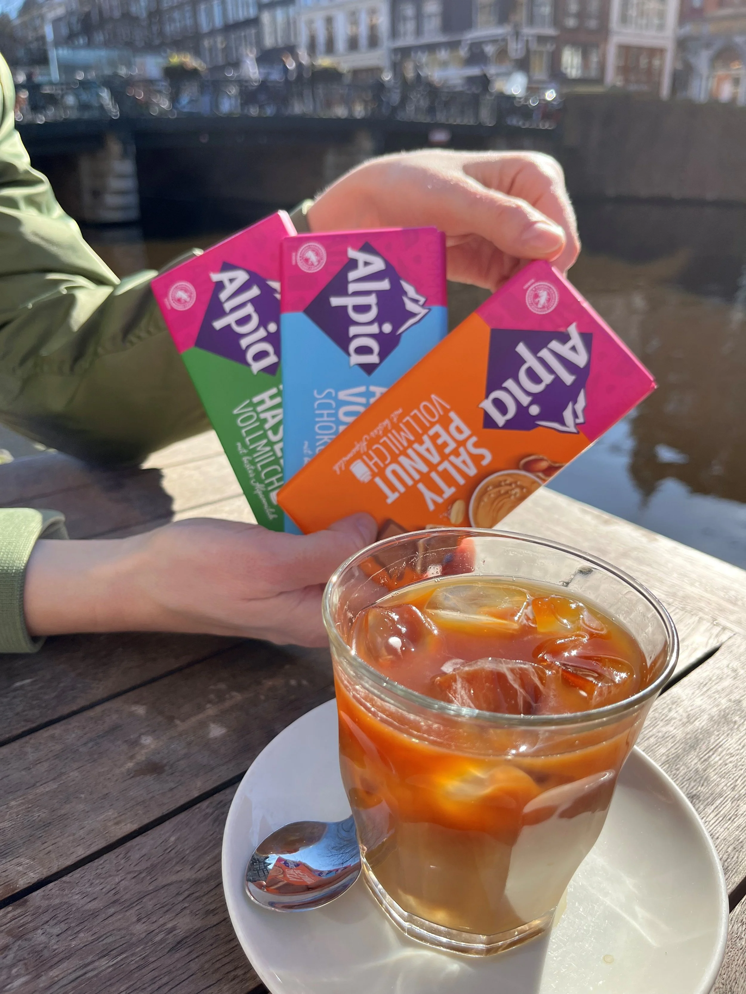 Alpia Salty Peanut Tafel beim Kaffeetrinken in der Sonne in Amsterdam – Süß-salziger Schokoladengenuss passend zur entspannten Kaffeepause im Freien.
