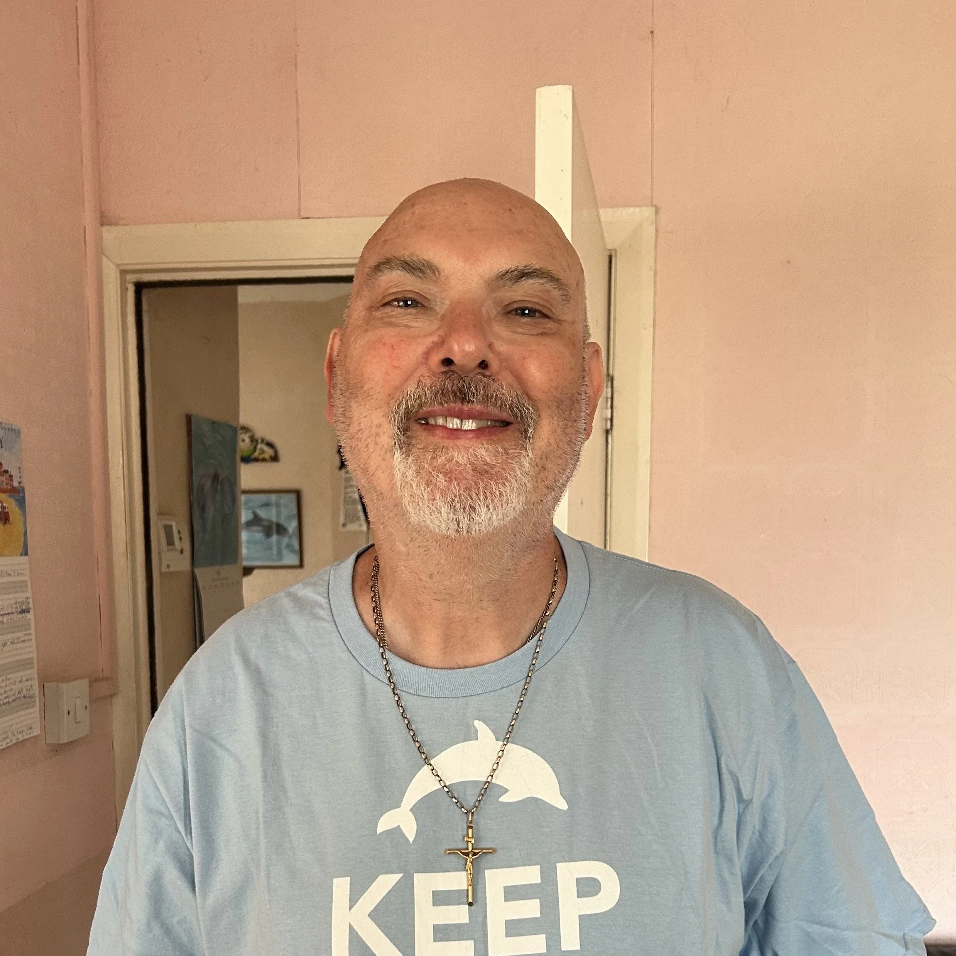 A man with a beard in a blue tshirt smiling