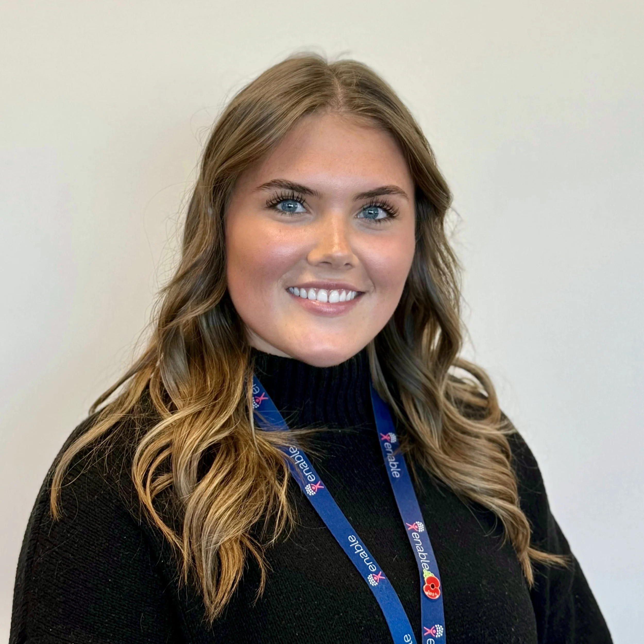 Smiling person with brown hair wearing a black shirt and a lanyard.