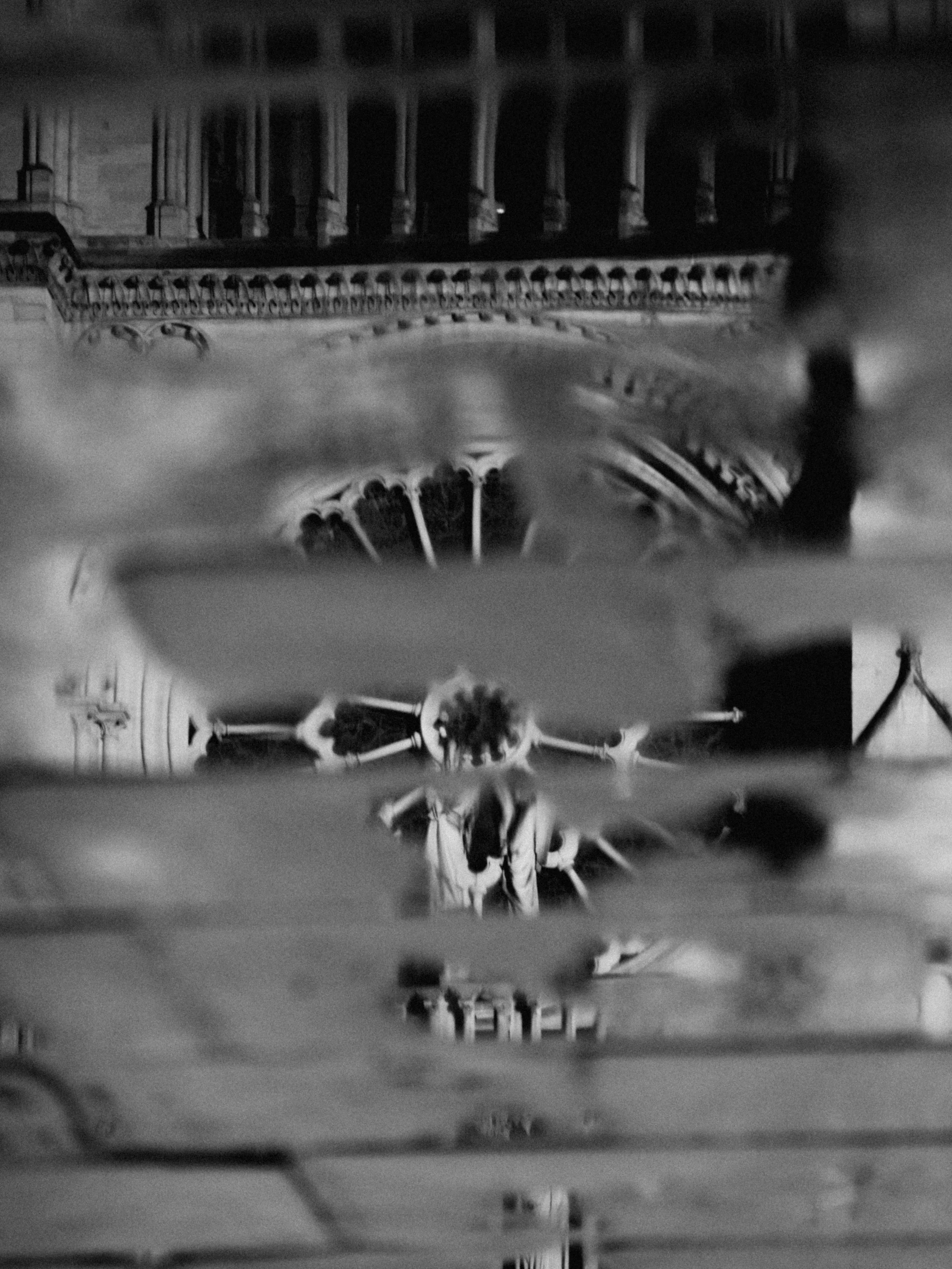 View of the Notre-Dame Cathedral in Paris, France, seen through a blurred glass surface, in black and white.